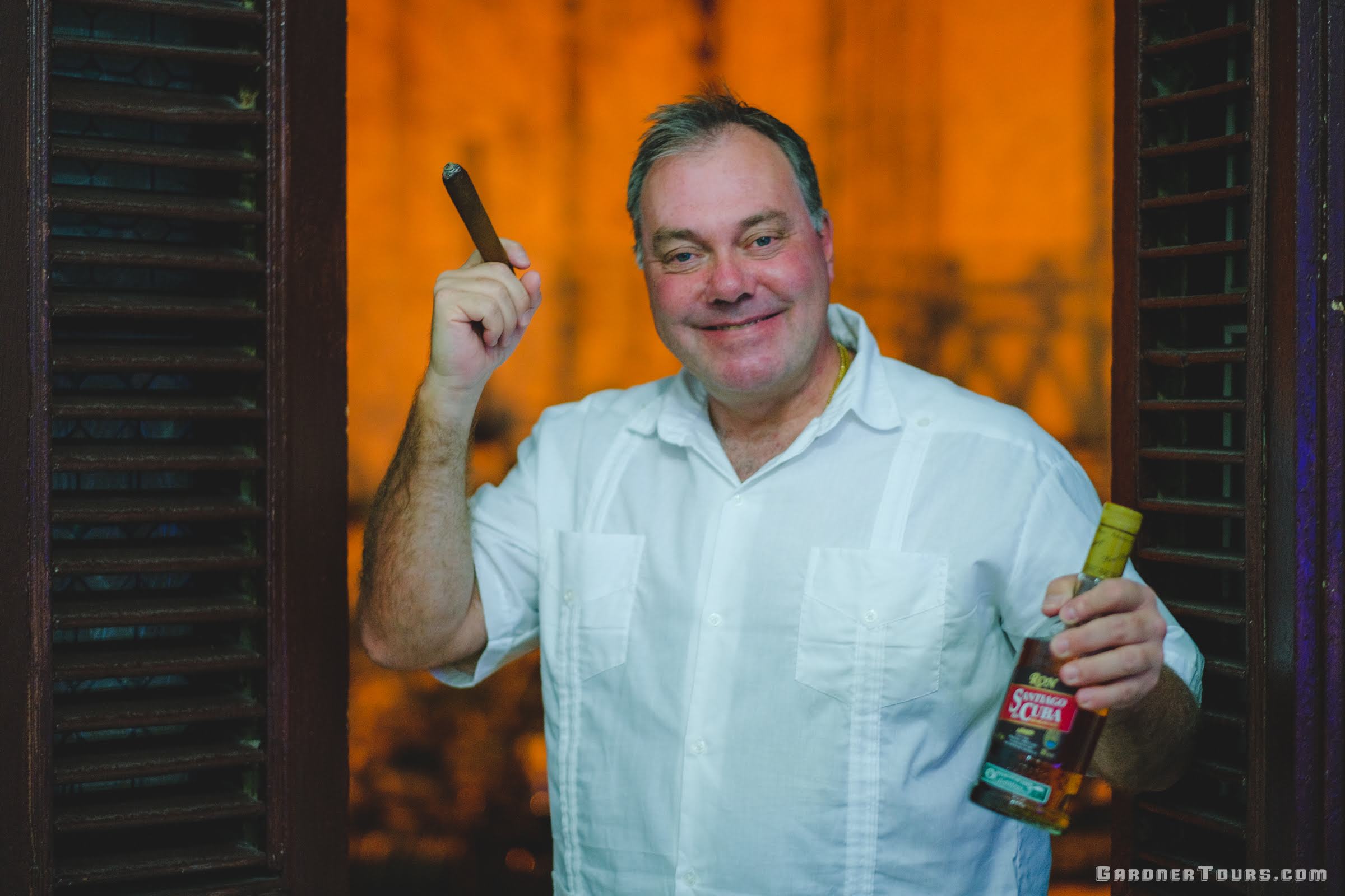 Man smoking Cuban Cigar and holding a bottle of Santiago de Cuba Rum in Havana, Cuba