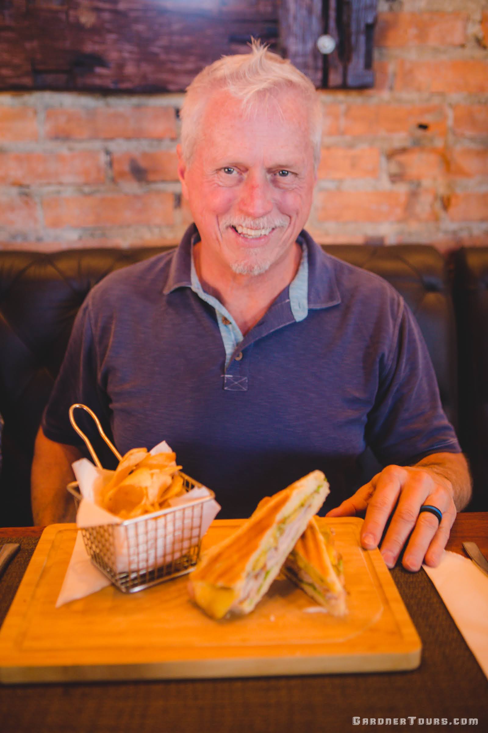 Handsome man in a blue shirt enjoying a Cuban Sandwich and homemade chips at Restaurant Paladar Cubar in Viñales, Cuba