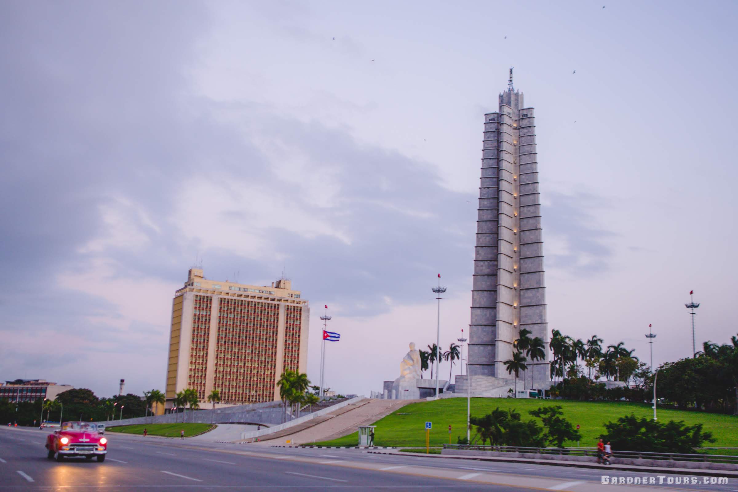 Pink Chevrolet Classic Car Convertible driving in front of the Tower of the Revolution in Havana, Cuba