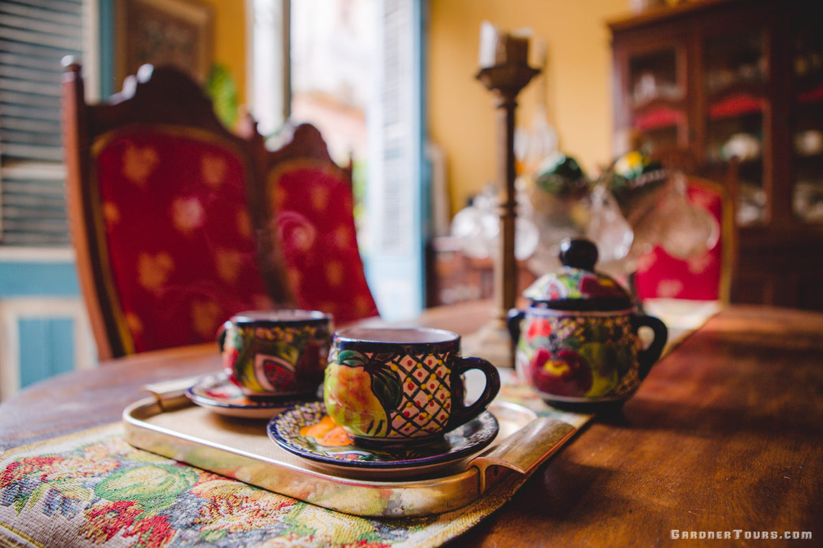 A warm cup of Cuban coffee sits on an antique dining table in a colorful dining room at a casa particular BnB in Old Havana, Cuba