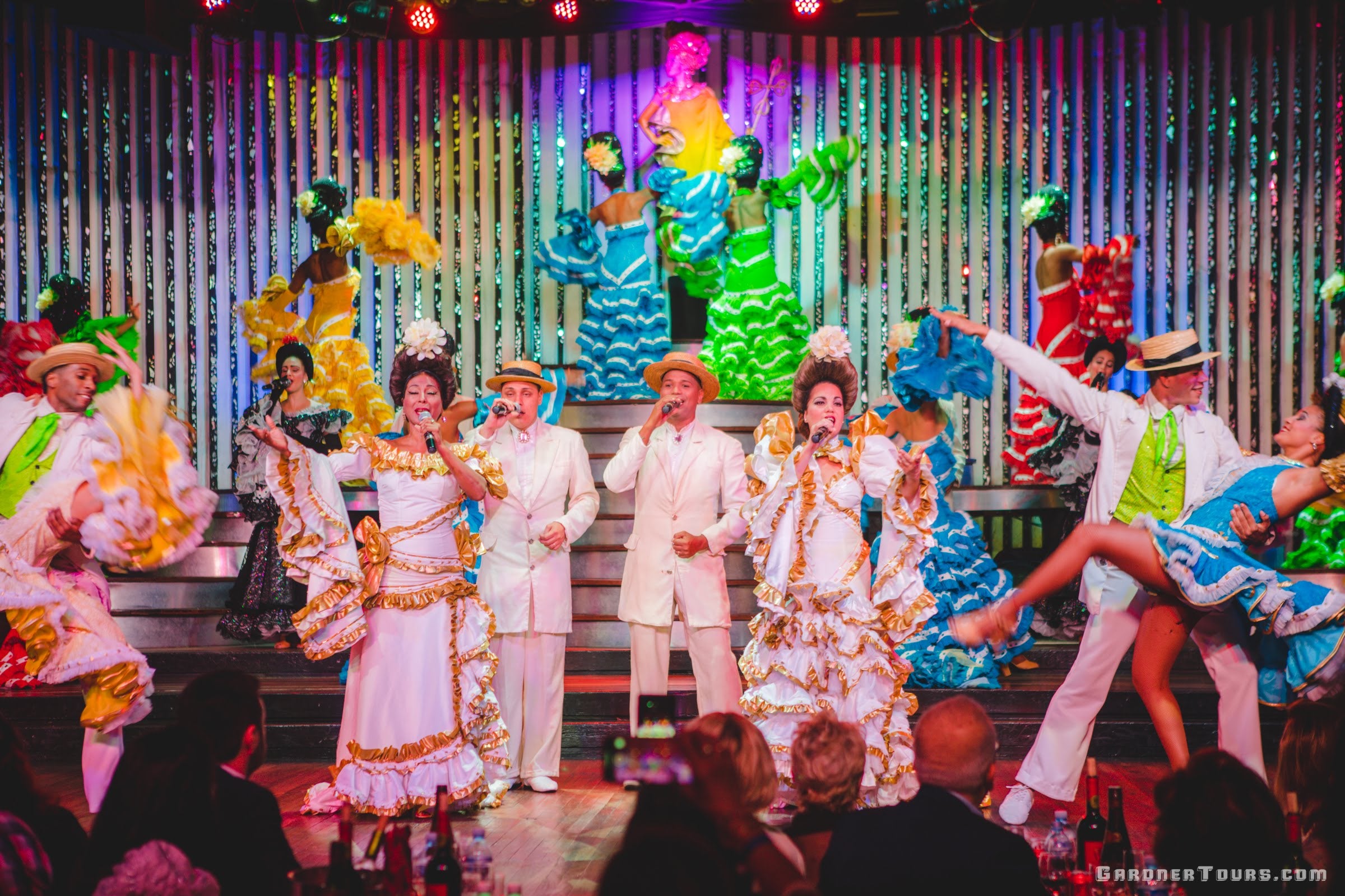 Men and women singers and dancers in colorful outfits performing at the Cabaret Parisien's Big Show in the Hotel Nacional in Havana, Cuba