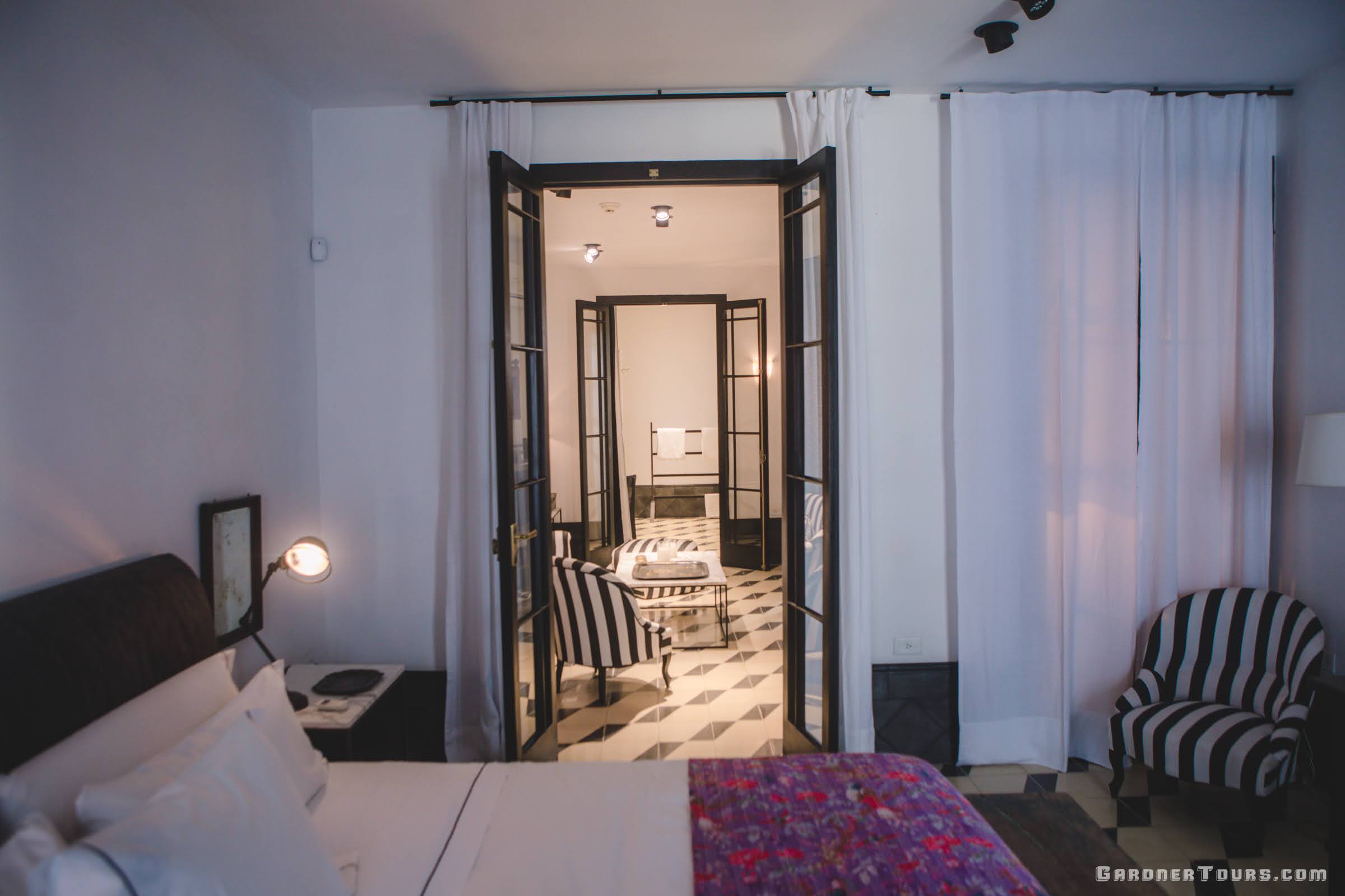 Luxury Bedroom with Lush Bed and Relaxing Living Room with Black and White and Purple Flowered Decor at 5-star Luxury Accommodations in Old Havana, Cuba
