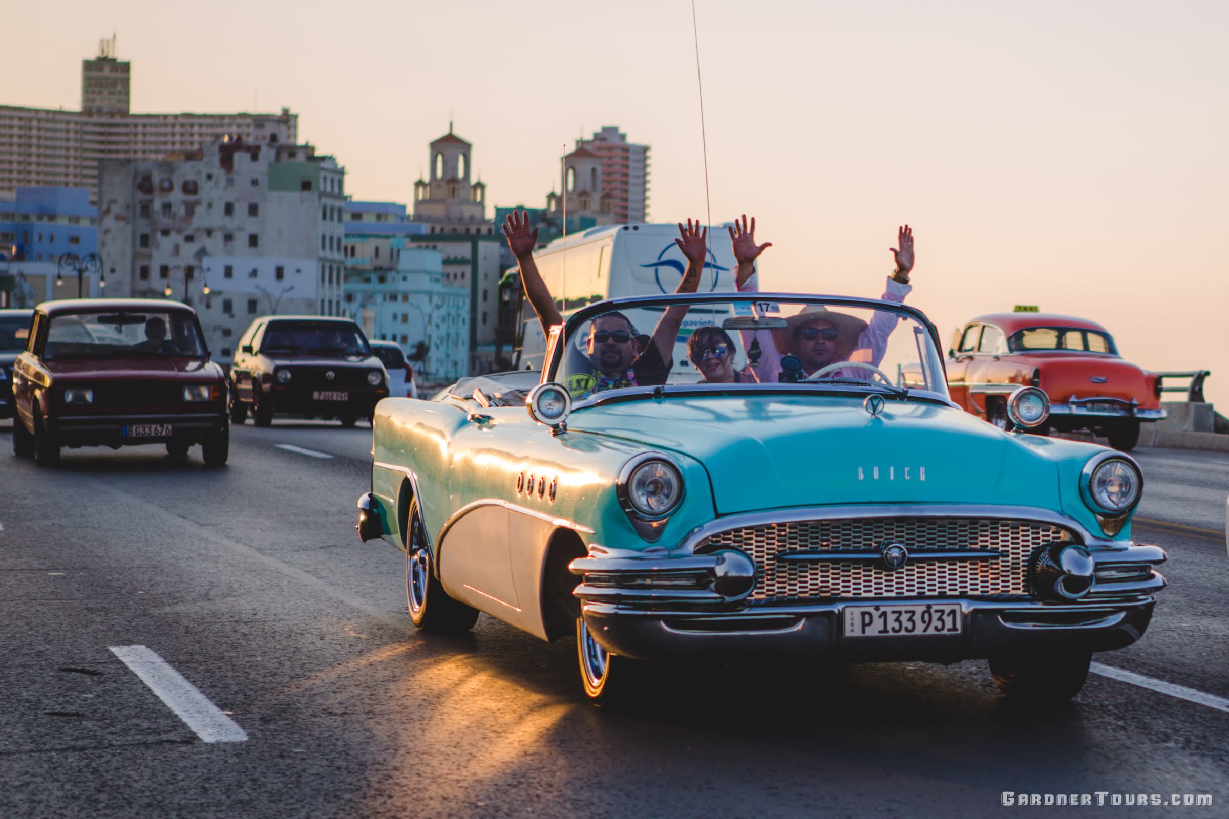 Group of Friends riding in Classic American Car Convertible with their hands in the air on the Malecon in Havana, Cuba