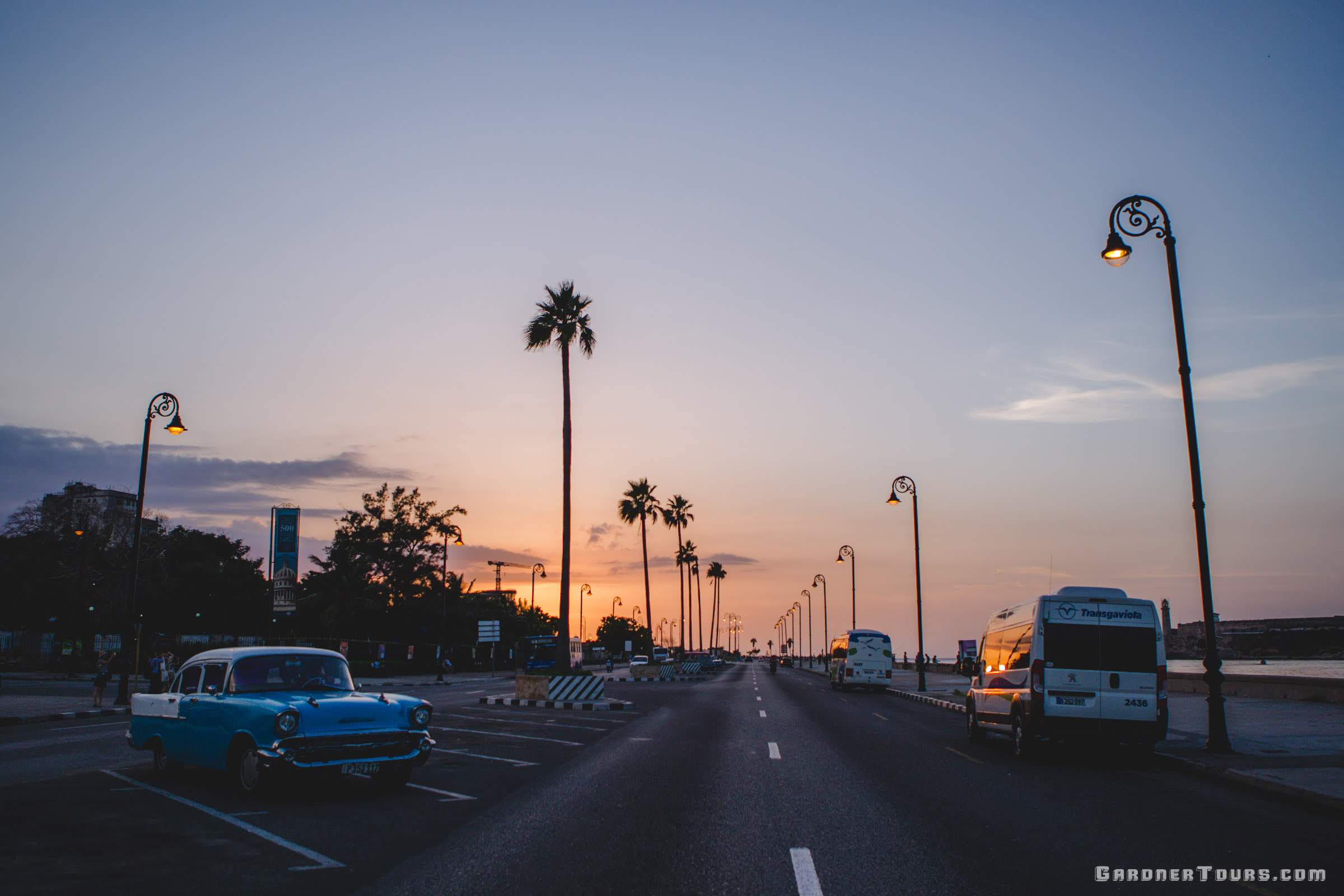 Gardner Tours Cuba Travels The orange sun sets over the streets of Old Havana with a blue 1957 Chevrolet Bel Air parked