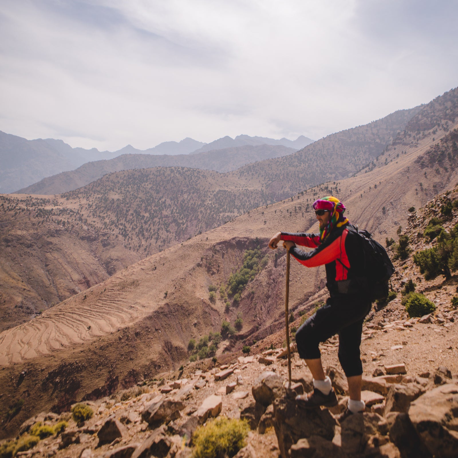 Gardner Tours Morocco Mountains Tour Man in red jacket and black pants hiking the High Atlas Mountains in Morocco