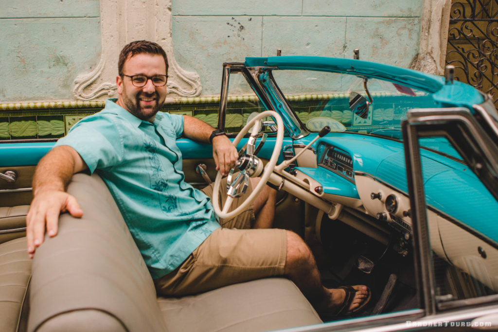 Colby Gardner, founder of Gardner Tours, driving a vintage turquoise 1954 Mercury convertible in Havana, Cuba. The heritage-inspired style reflects the personalized, high-end travel experience of our Cuban tours.