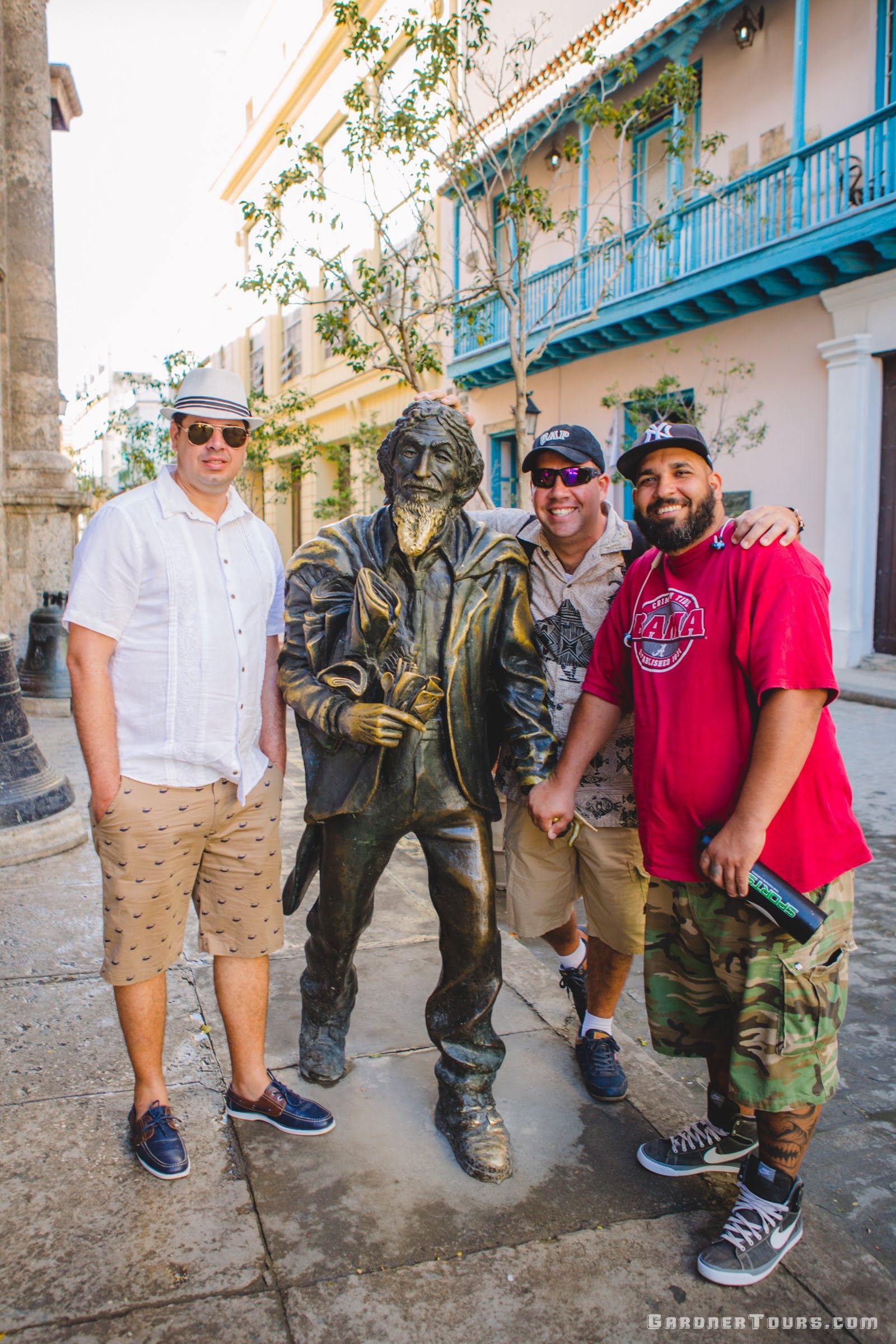 Gardner Tours Cuban Tour Guide Albert smiling with two friends at the Caballero de Paris statue in Old Havana, Cuba