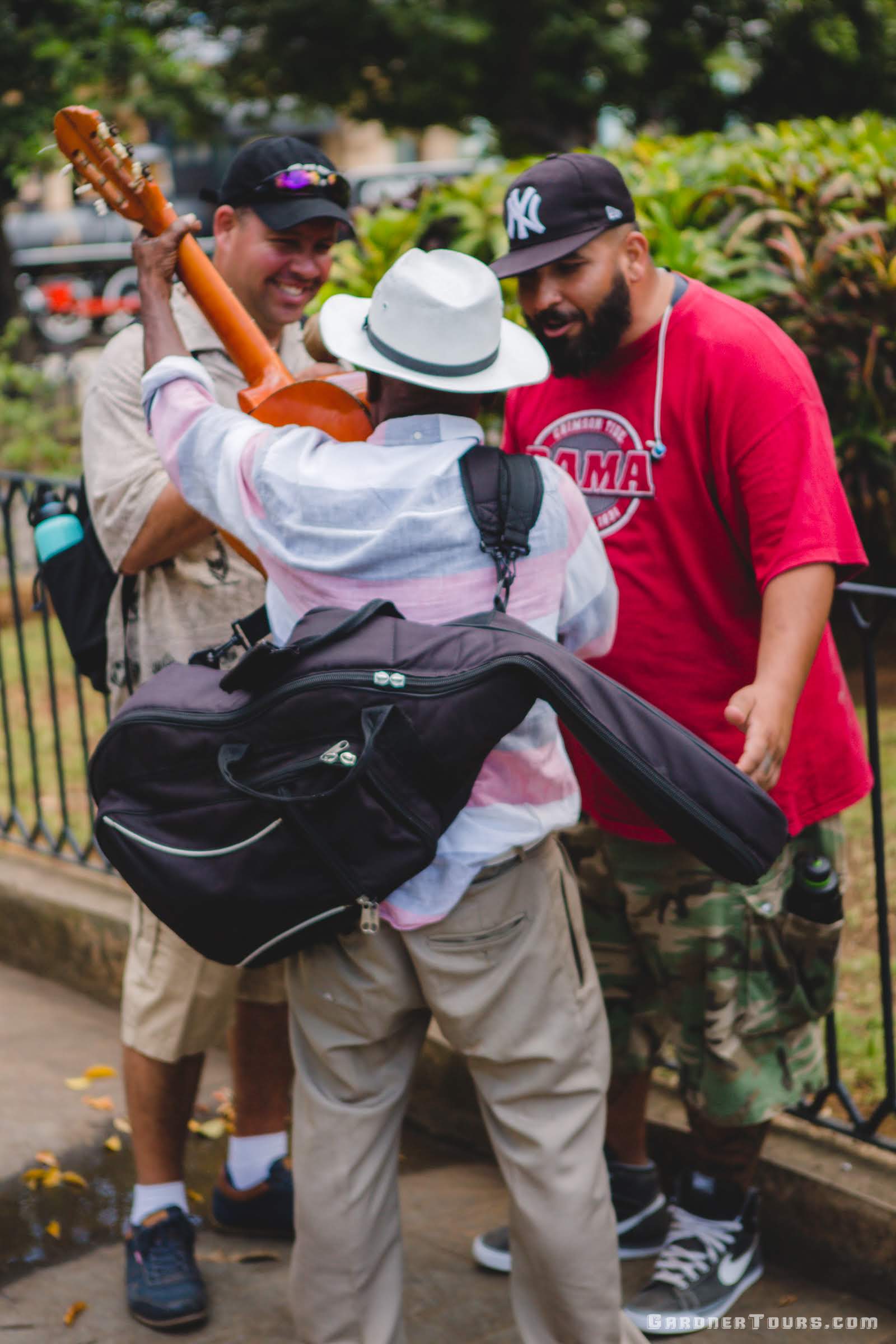 Gardner Tours Cuban Tour Guides Albert and Yunior talking to a local musician in Plaza de Armas Old Havana, Cuba