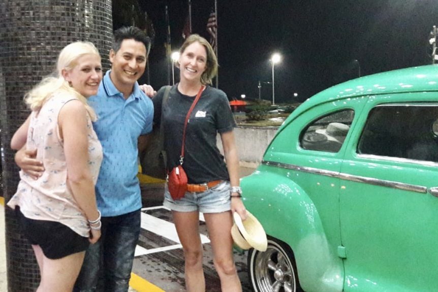 Gardner Tours Cuban Tour Guide Carlos with two Dutch travelers in front of a green classic car in Havana, Cuba