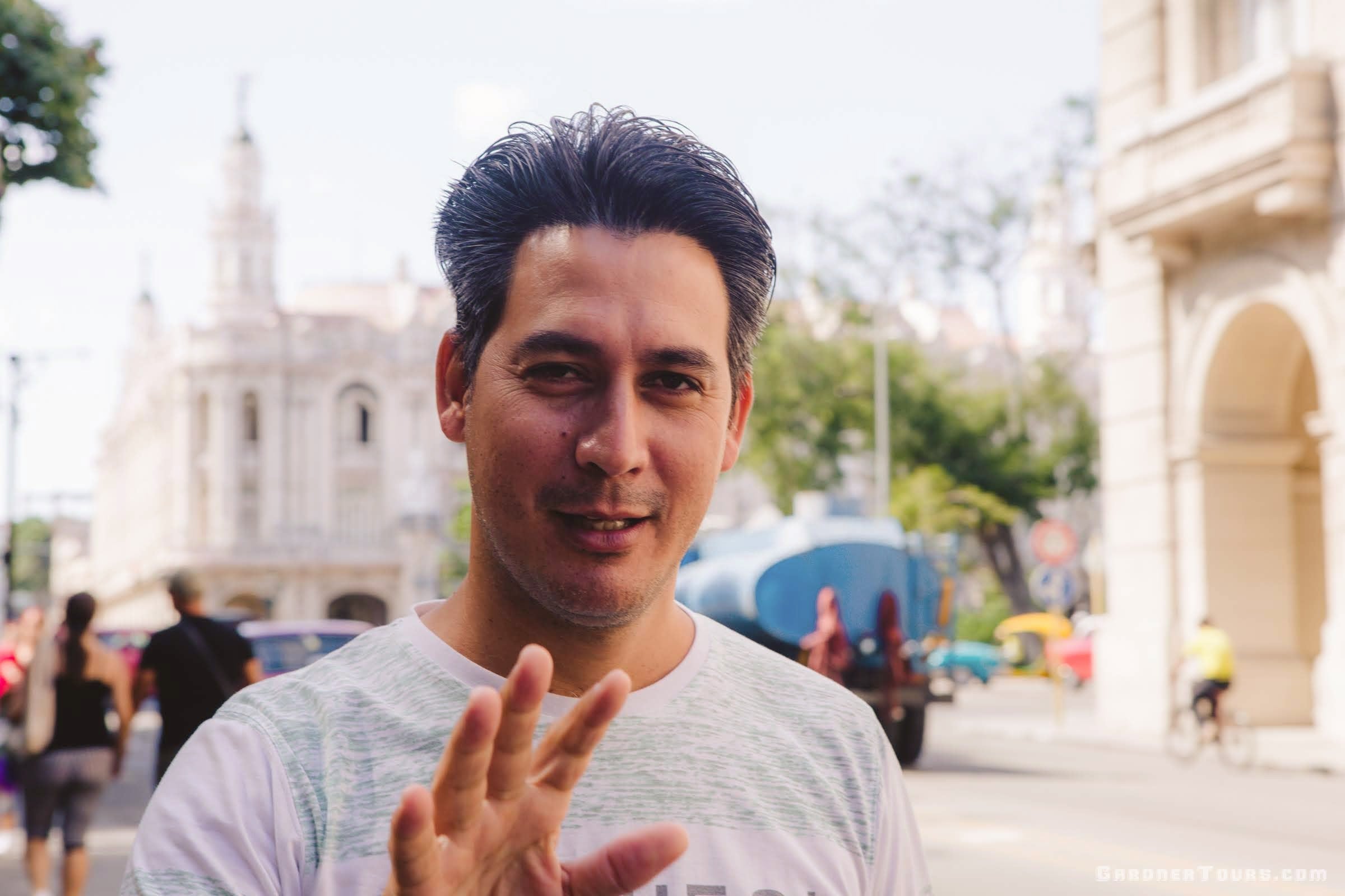 Gardner Tours Cuban Tour Guide Carlos with his hand up and talking in the streets of Old Havana, Cuba