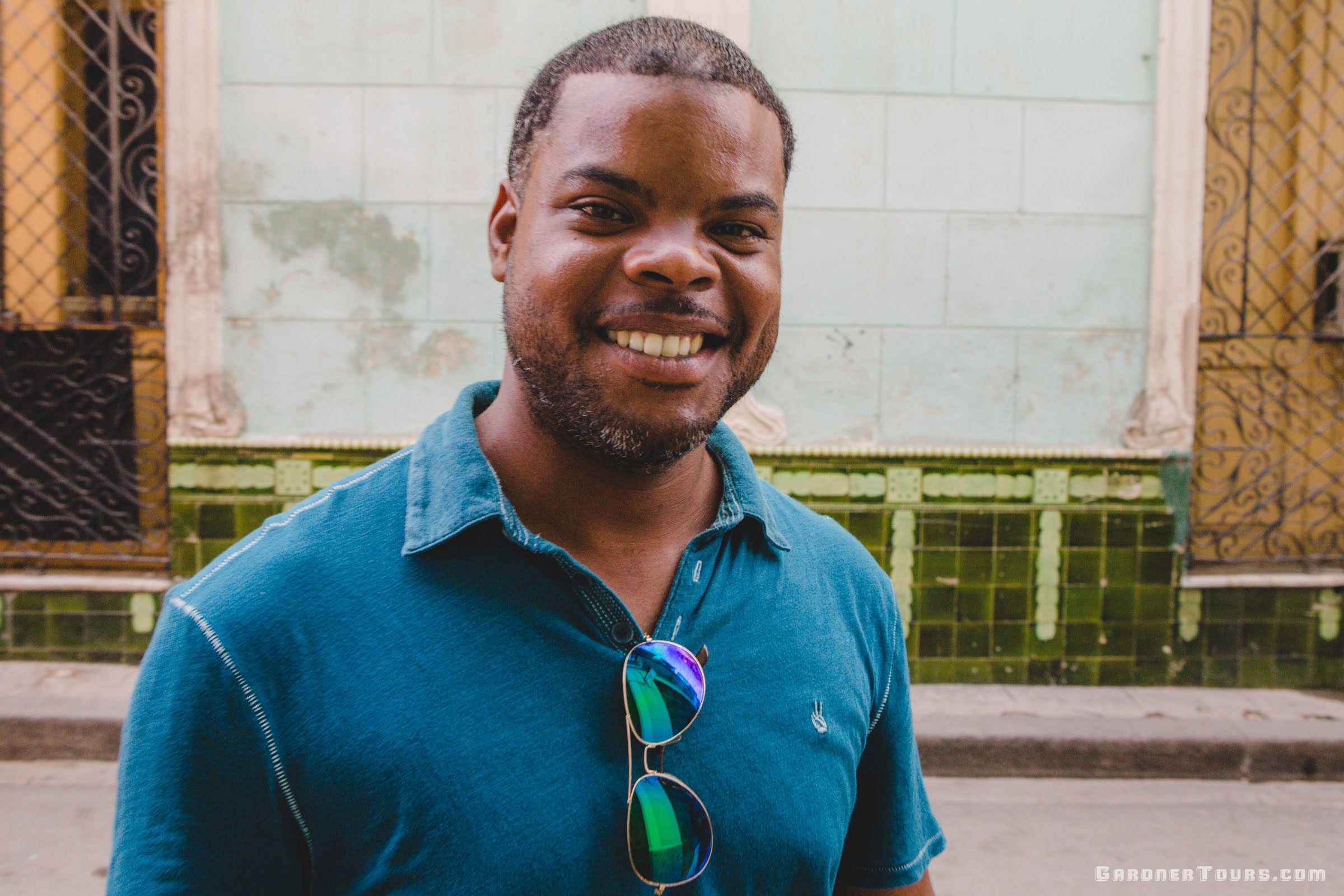 Gardner Tours Cuban Tour Guide Michel wearing a blue shirt and sunglasses smiles in the street of Old Havana, Cuba