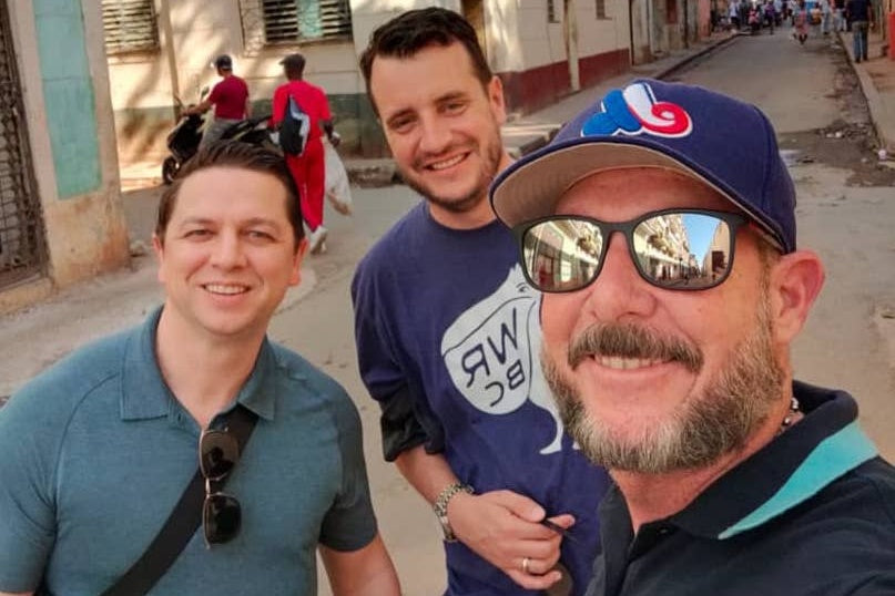 Gardner Tours Cuban Tour Guide Yedi smiling with two American men travelers as they walk the streets of Old Havana, Cuba