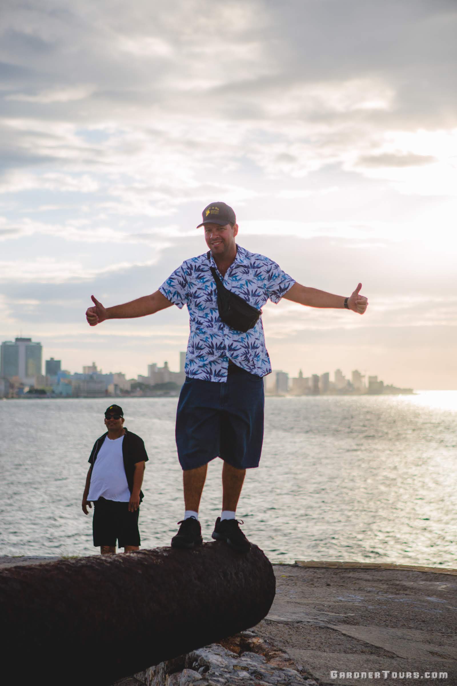Gardner Tours Cuban Tour Guide Yunior standing on top of a cannon at El Morro Castle in Havana, Cuba
