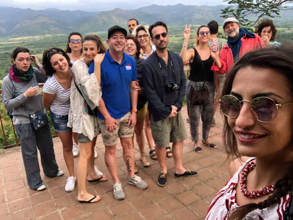 Gardner Tours Cuban Tour Guide Yedi posing with a group of his travelers at the Sugar Valley Viewpoint in Trinidad, Cuba