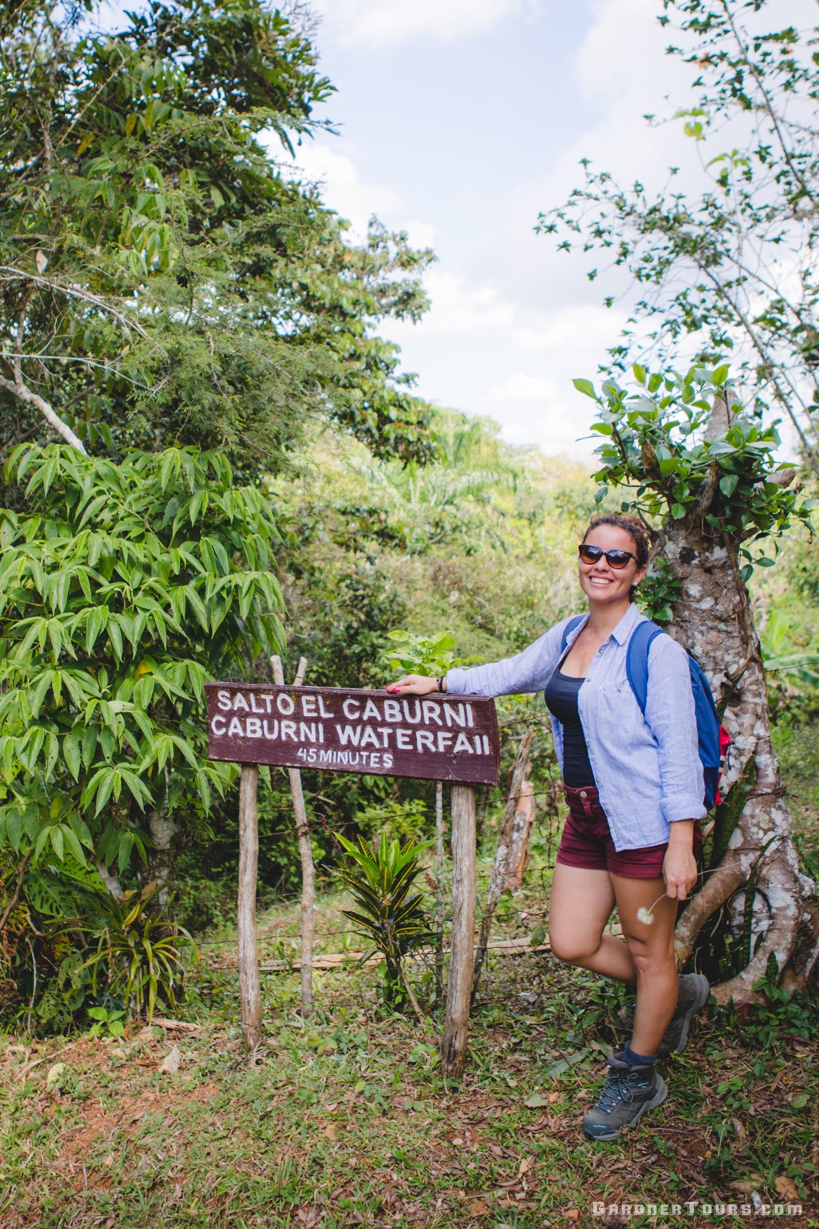 Gardner Tours Cuban Tour Guide Zeydi Posing in front of the Salto el Caburni Waterfall Sign on a hike in Topes de Collantes National Park Cuba