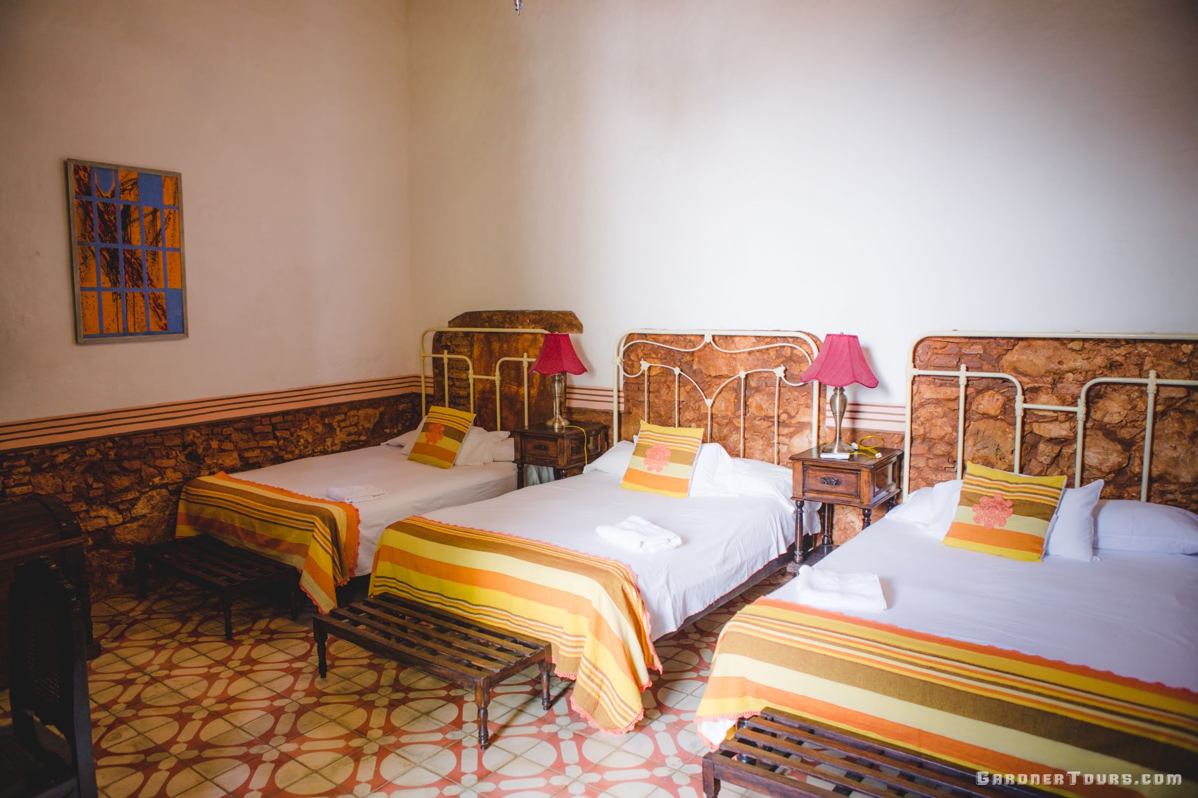 Large brown and white antique bedroom with three big beds at a Casa Particular BnB in Trinidad, Cuba
