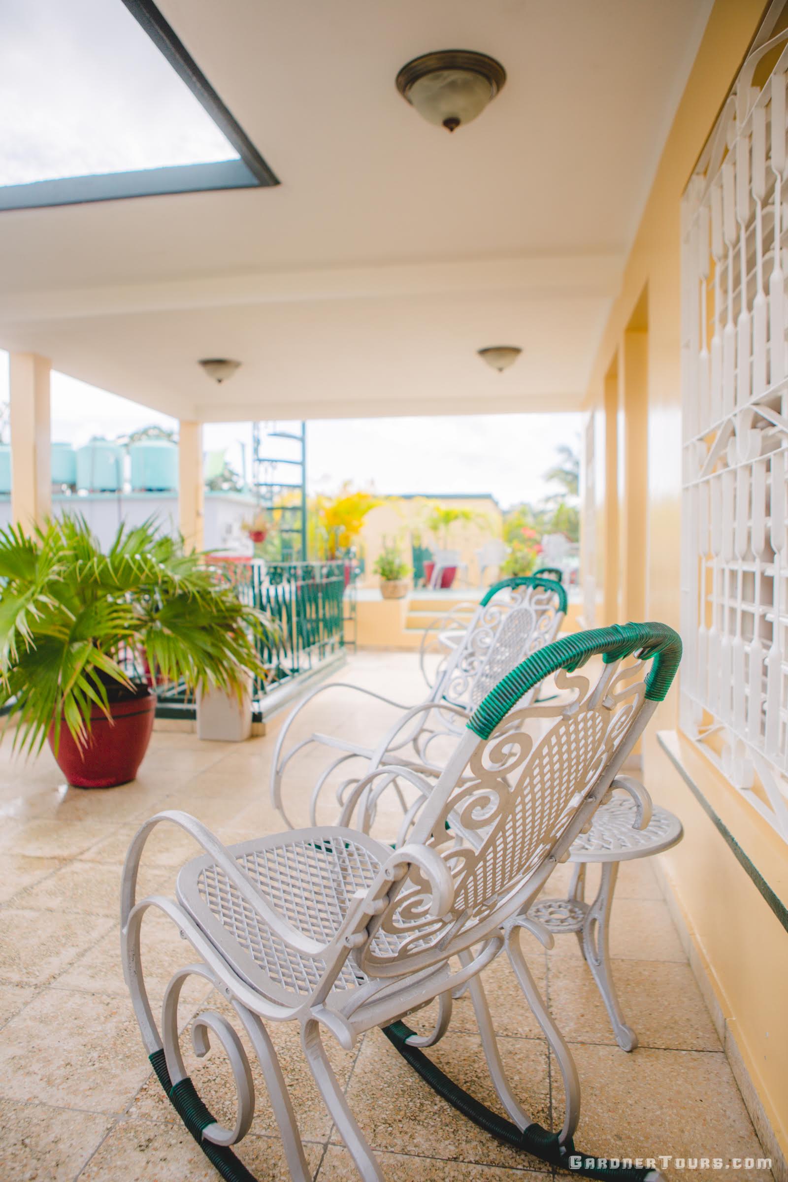 Gorgeous yellow and green Rooftop Porch Area with rocking chairs at a 3-star BnB in Vinales Cuba