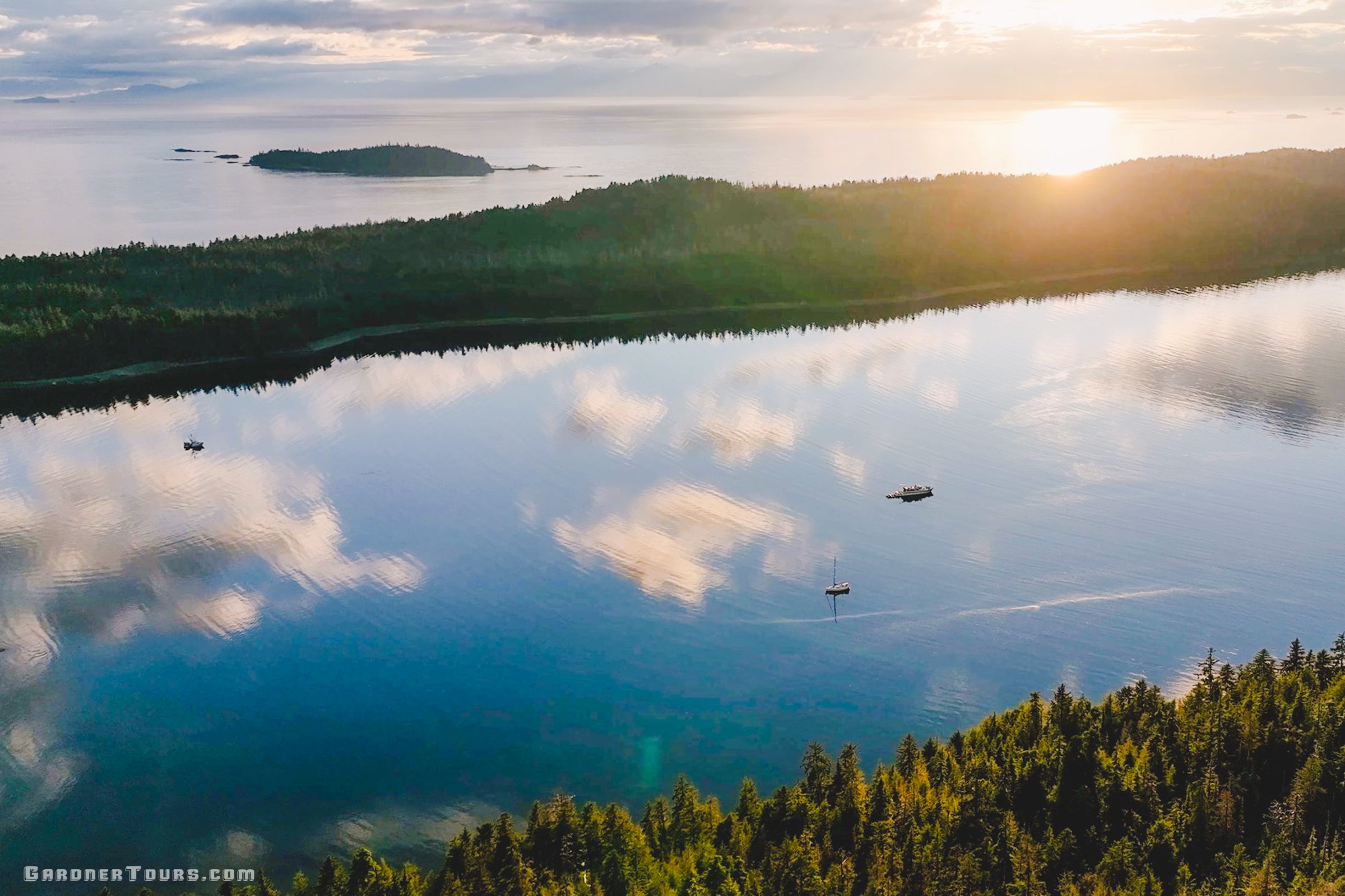 Drone photography of a private yacht and sailboat in a glass-calm cove in the Inside Passage.