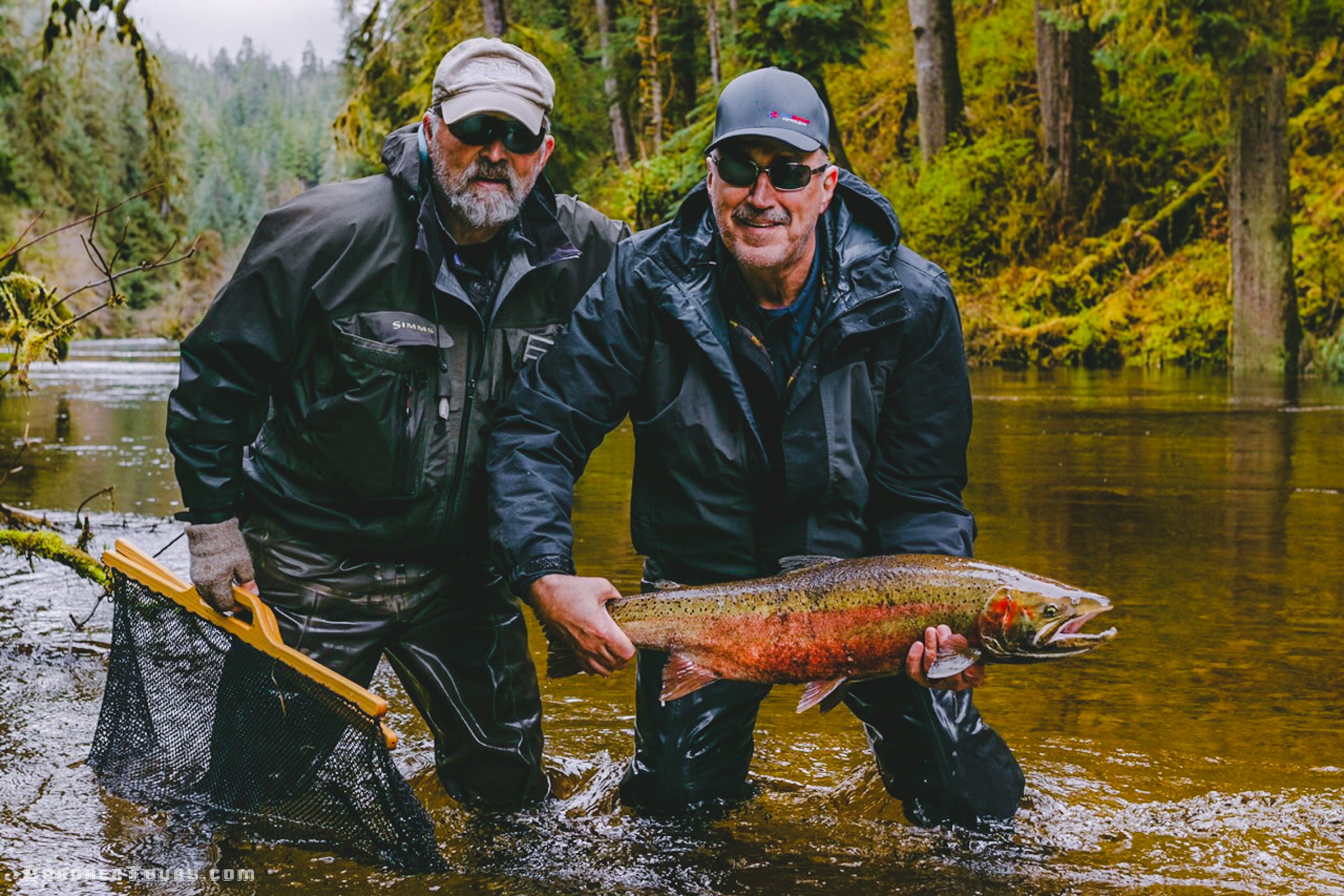 Two fishermen holding a large freshly caught salmon in a remote Southeast Alaska river.