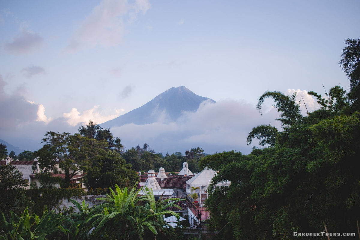 Scenic view of historic Antigua Guatemala tile rooftops with Agua Volcano surrounded by soft clouds