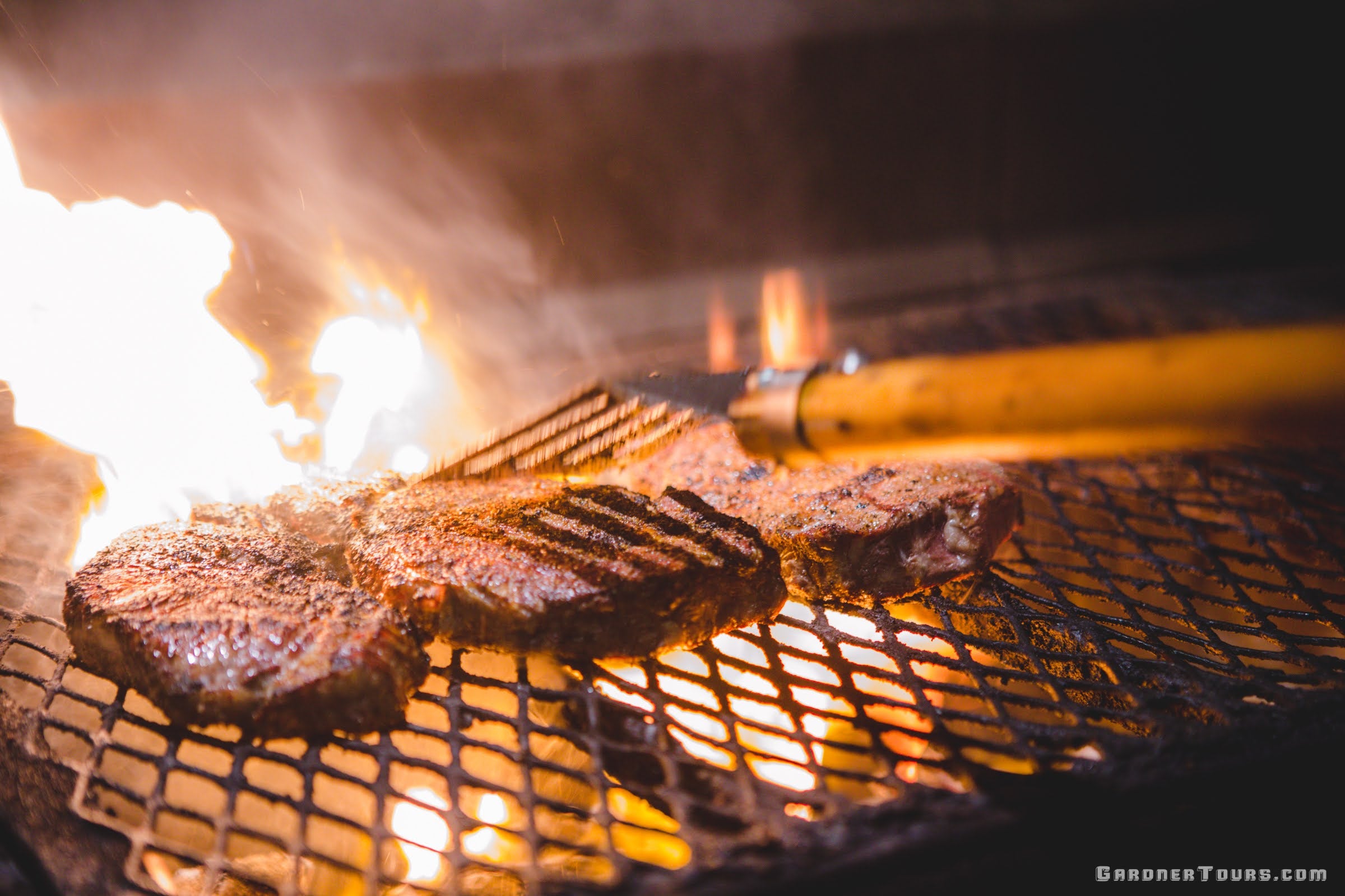 Thick-cut steaks sizzling over an open-flame grill for dinner at Leona General Store in Texas.