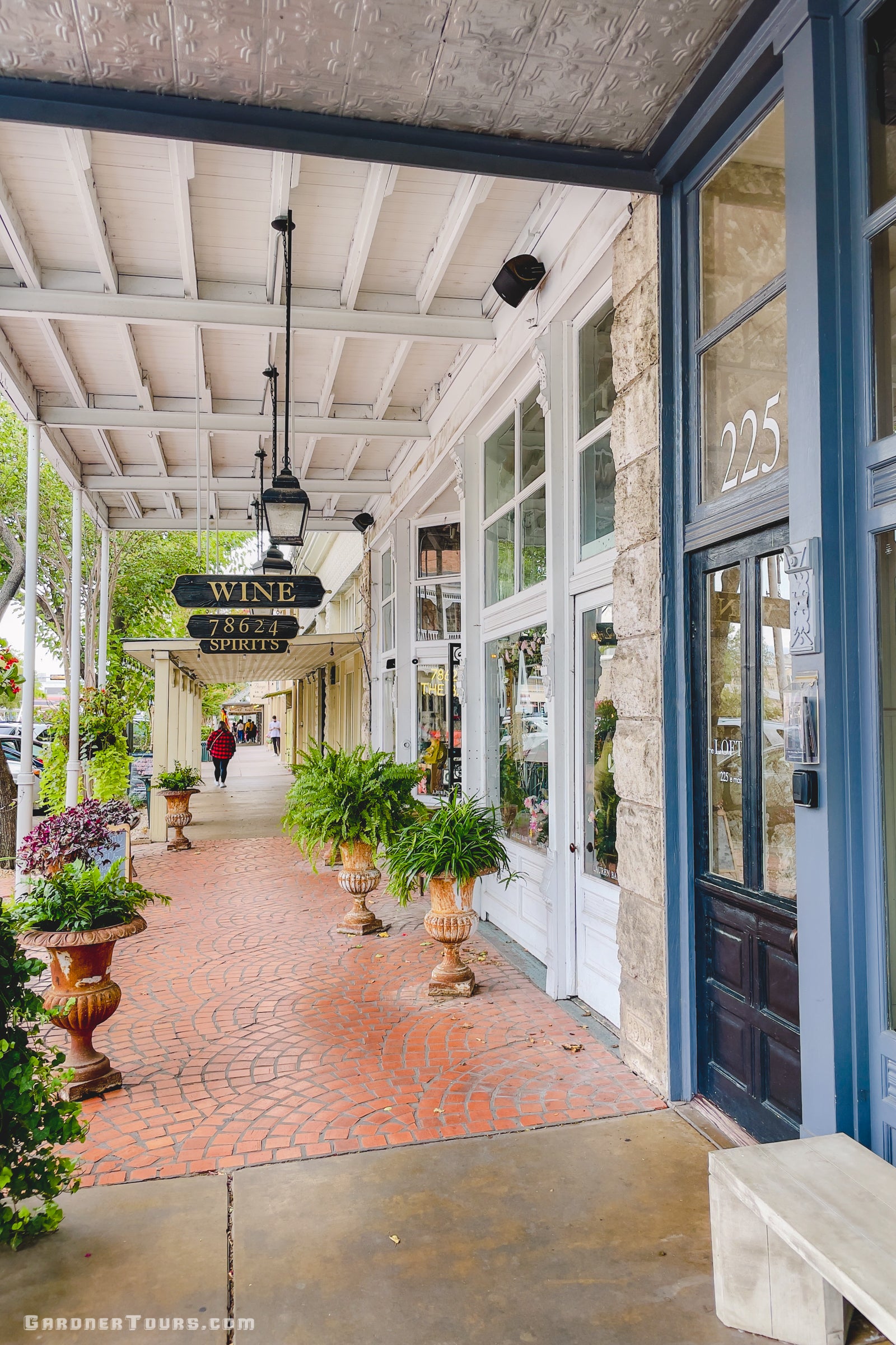 A beautiful white and blue storefront with a sign that says "wine" on Main Street in Fredericksburg, Texas.