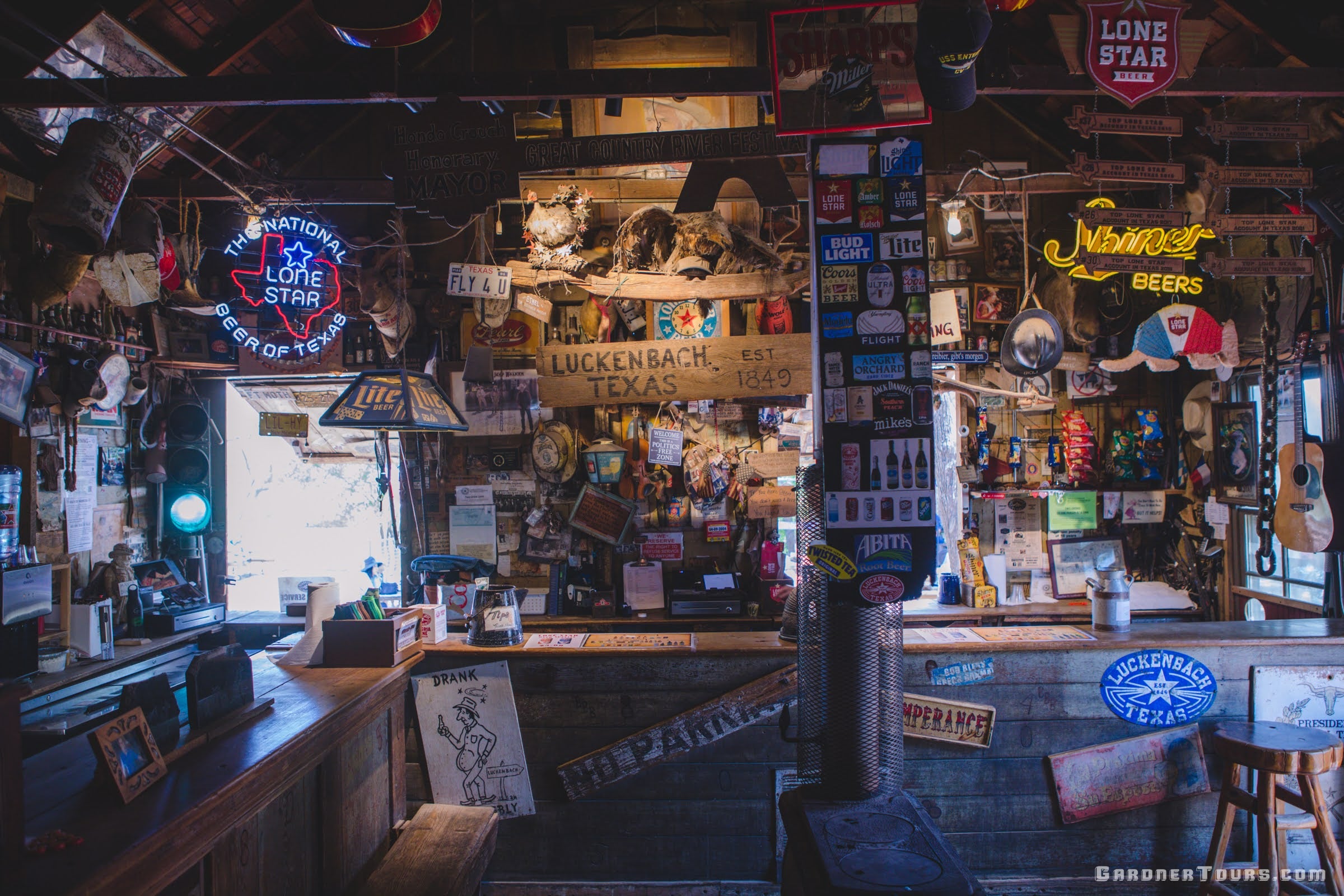 The Luckenbach bar with eclectic signs and neon beer signs on all of the walls in the Luckenbach Post Office in Luckenbach, Texas.
