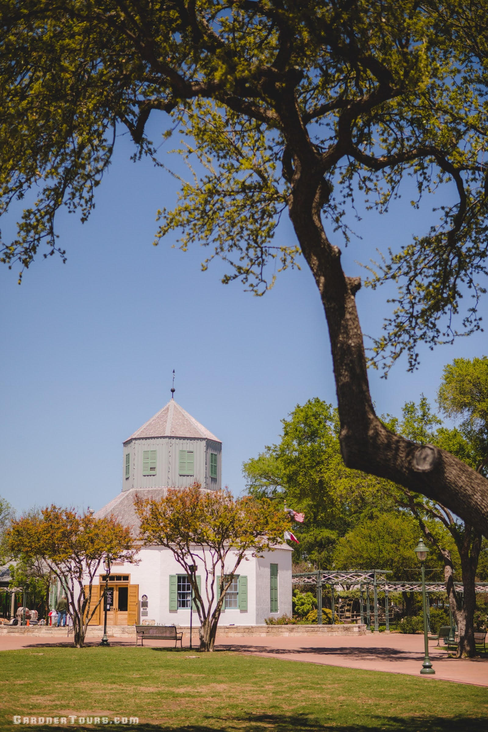 the original green and white vereins church in the shadow of oak trees in downtown fredericksburg texas