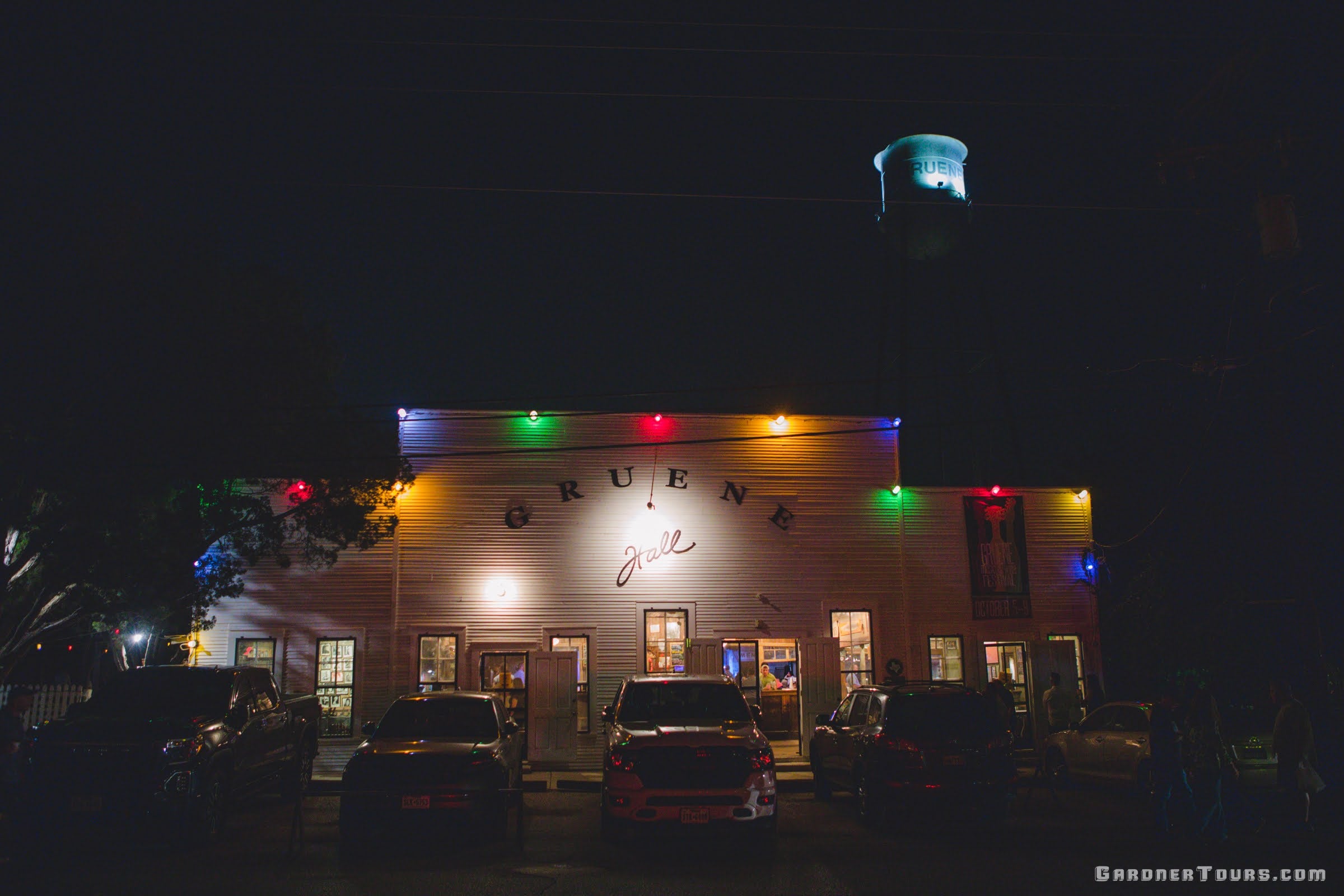 Gruene Hall at night with colorful Christmas lights, with the water tower visible in the background.