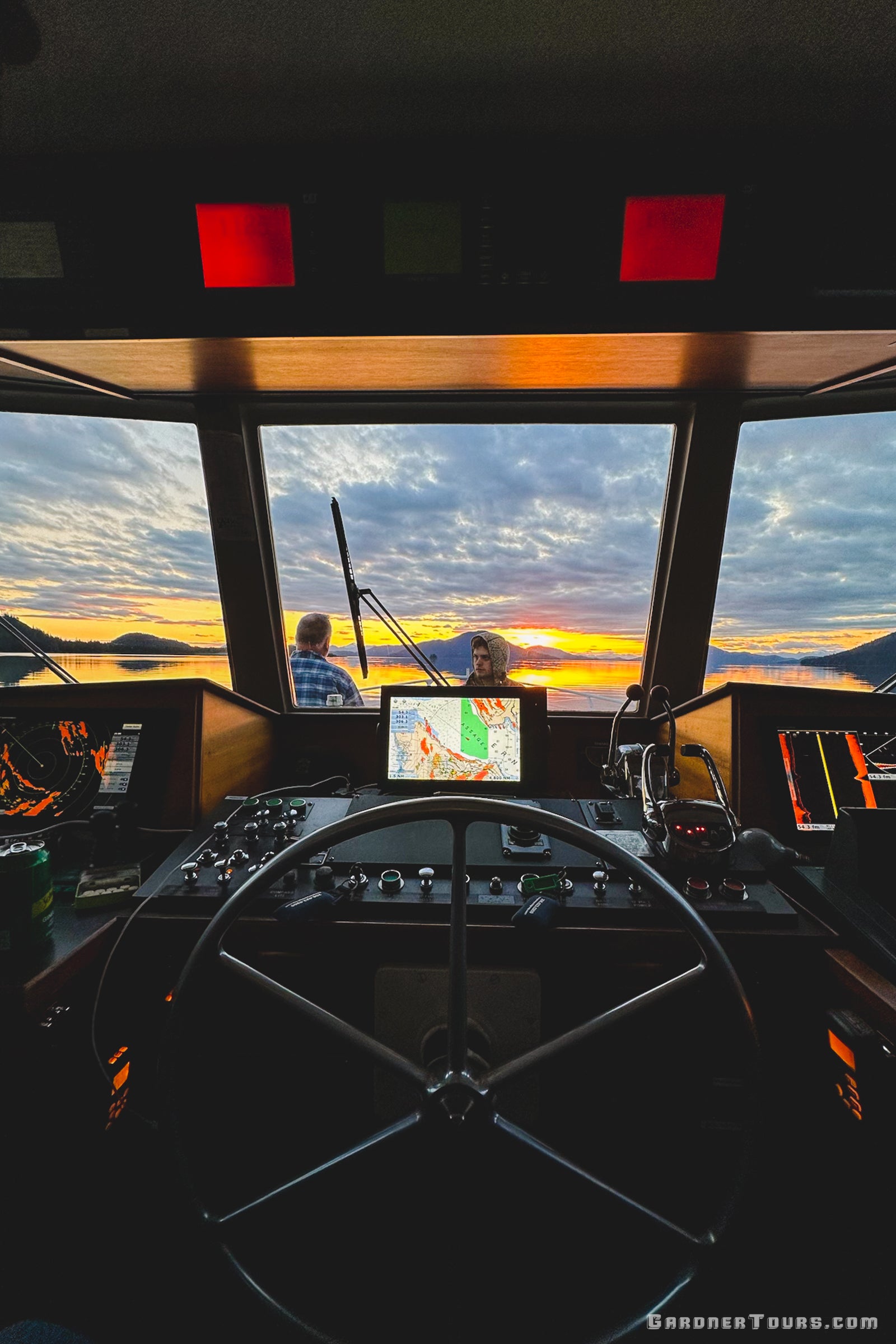 The view from the captain's wheelhouse during a sunset transit through the Alaskan wilderness.