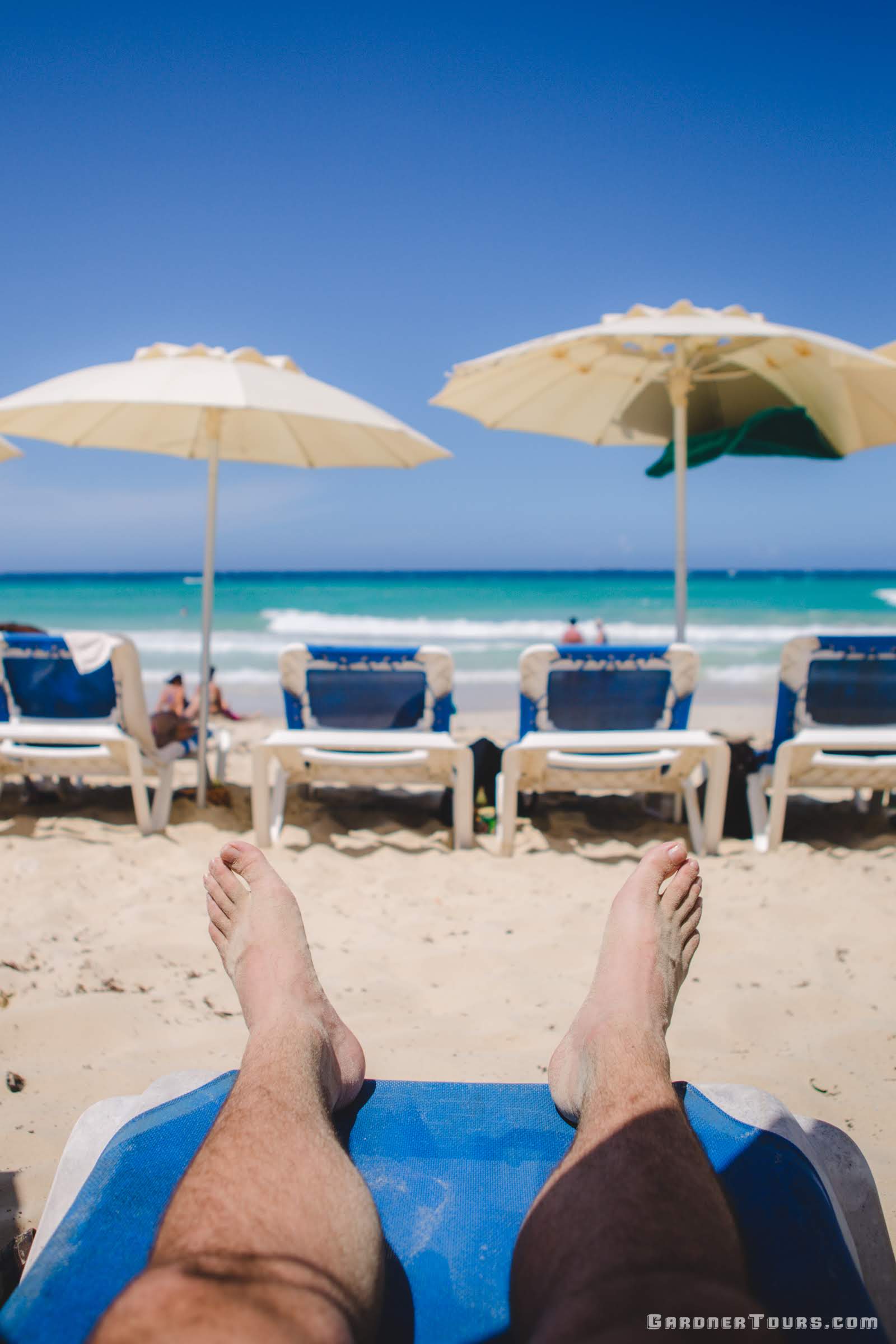 Man Relaxing Under Umbrella in the shade at the Playas del Este Beach Outside of Havana, Cuba