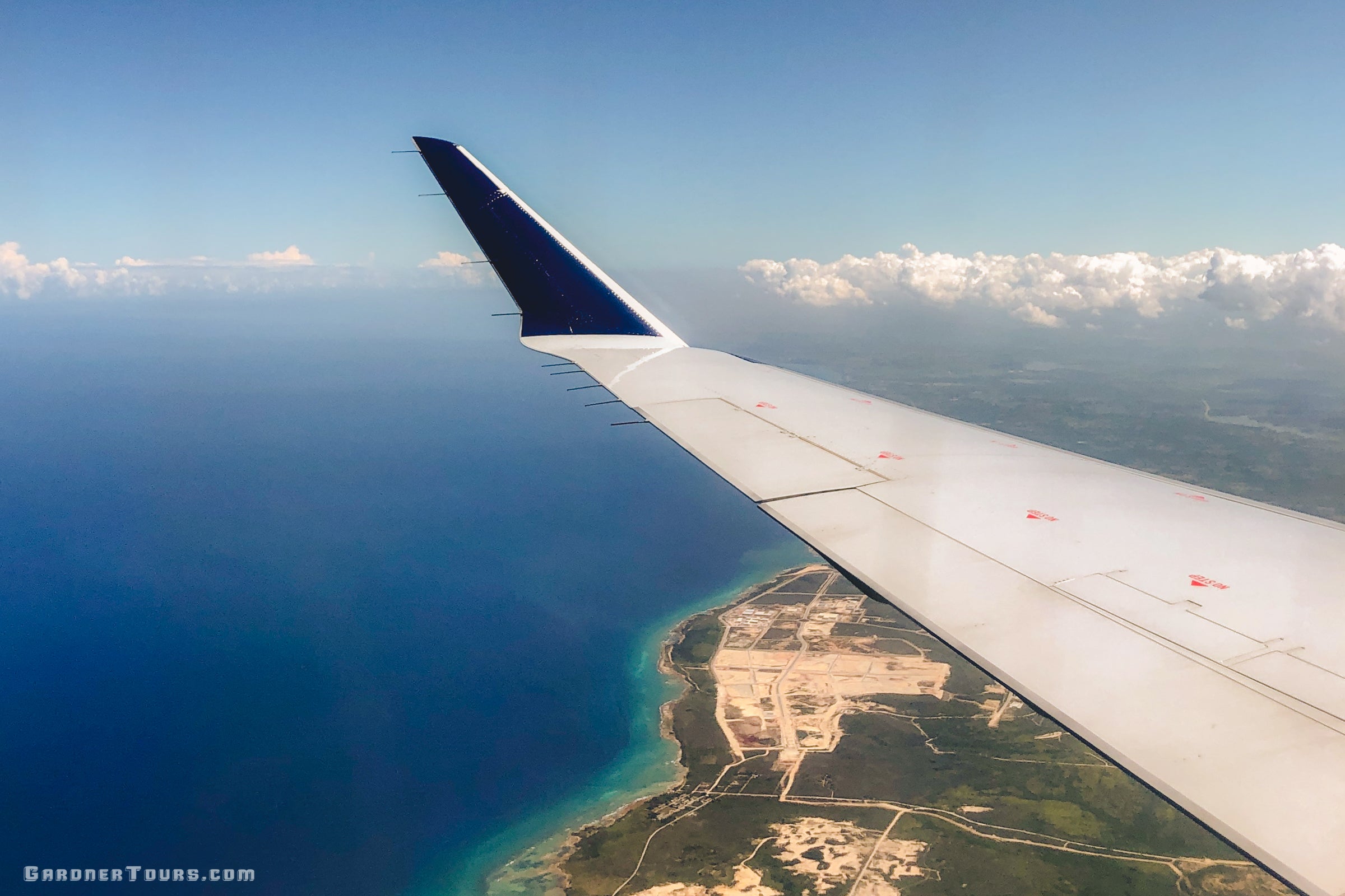 Gardner Tours Airplane Arriving over Blue Waters and Lush Lands in Havana, Cuba