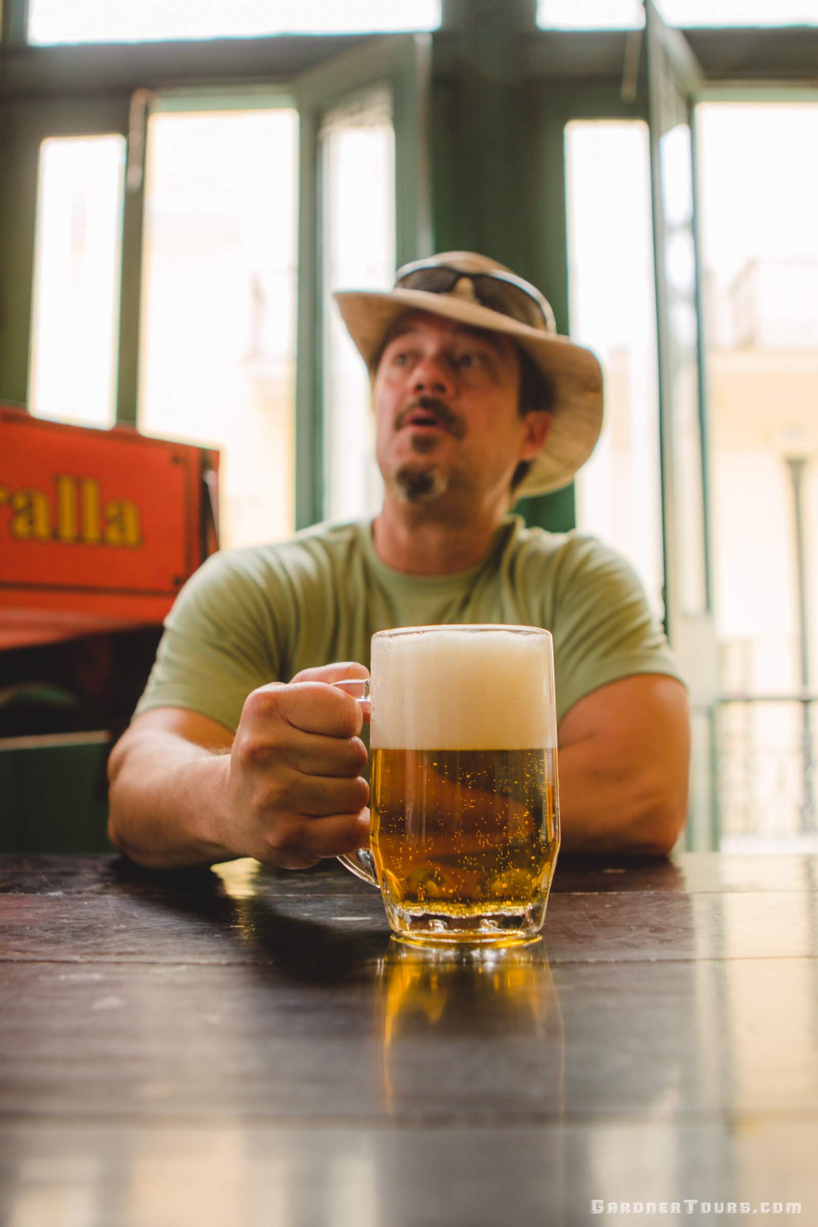 A man enjoying a large glass of blonde beer at the Cerveceria in Plaza Vieja, Old Havana, Cuba