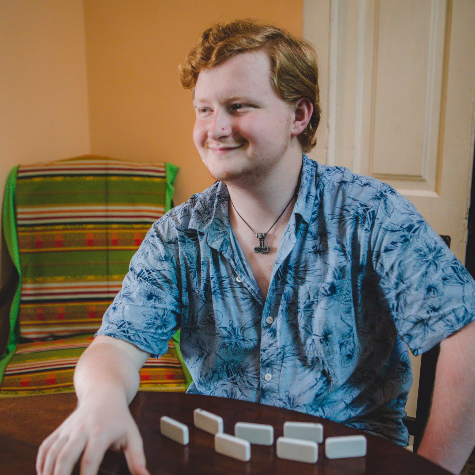 Gardner Tours Custom Cuba Tour with a Young Red Headed Man playing Dominoes and smiling in his blue shirt