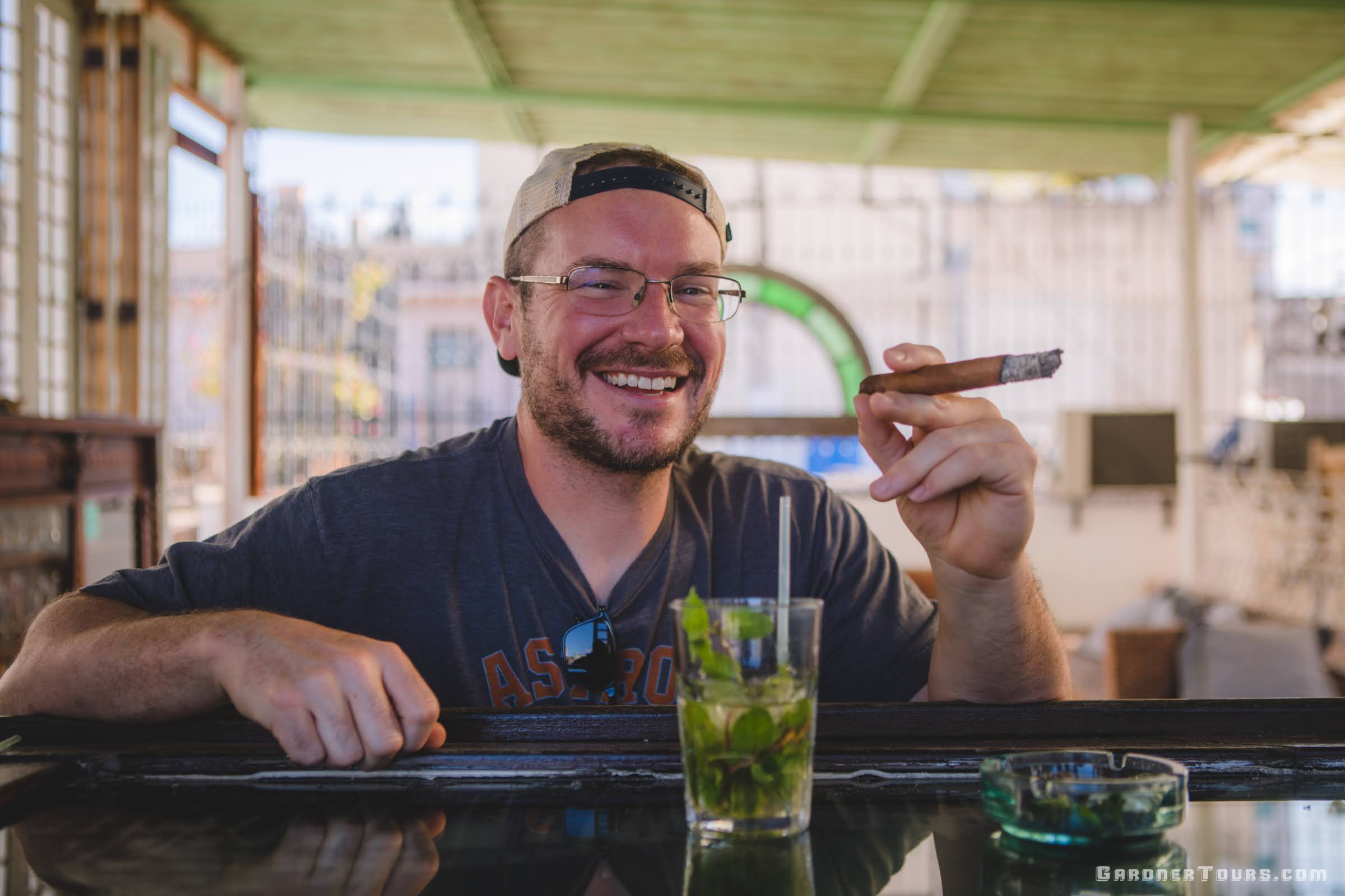Man Smoking Cuban Cigar and Drinking Mojito at Bar in Havana, Cuba