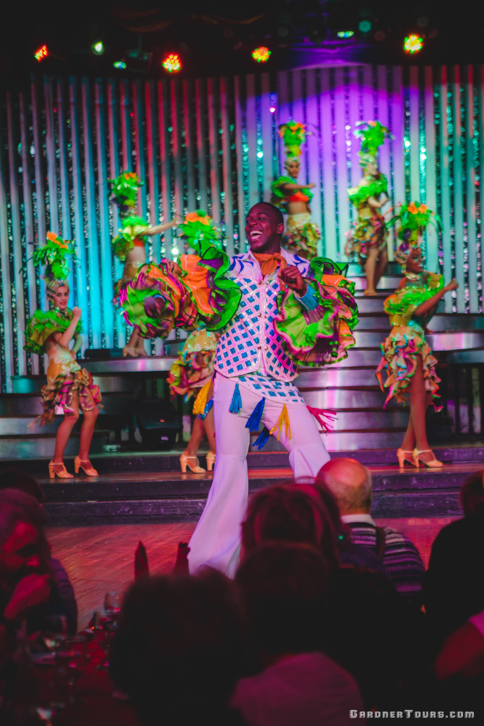 Lead male singer and many dancers in colorful outfits performing at the Cabaret Parisien's Big Show in the Hotel Nacional in Havana, Cuba