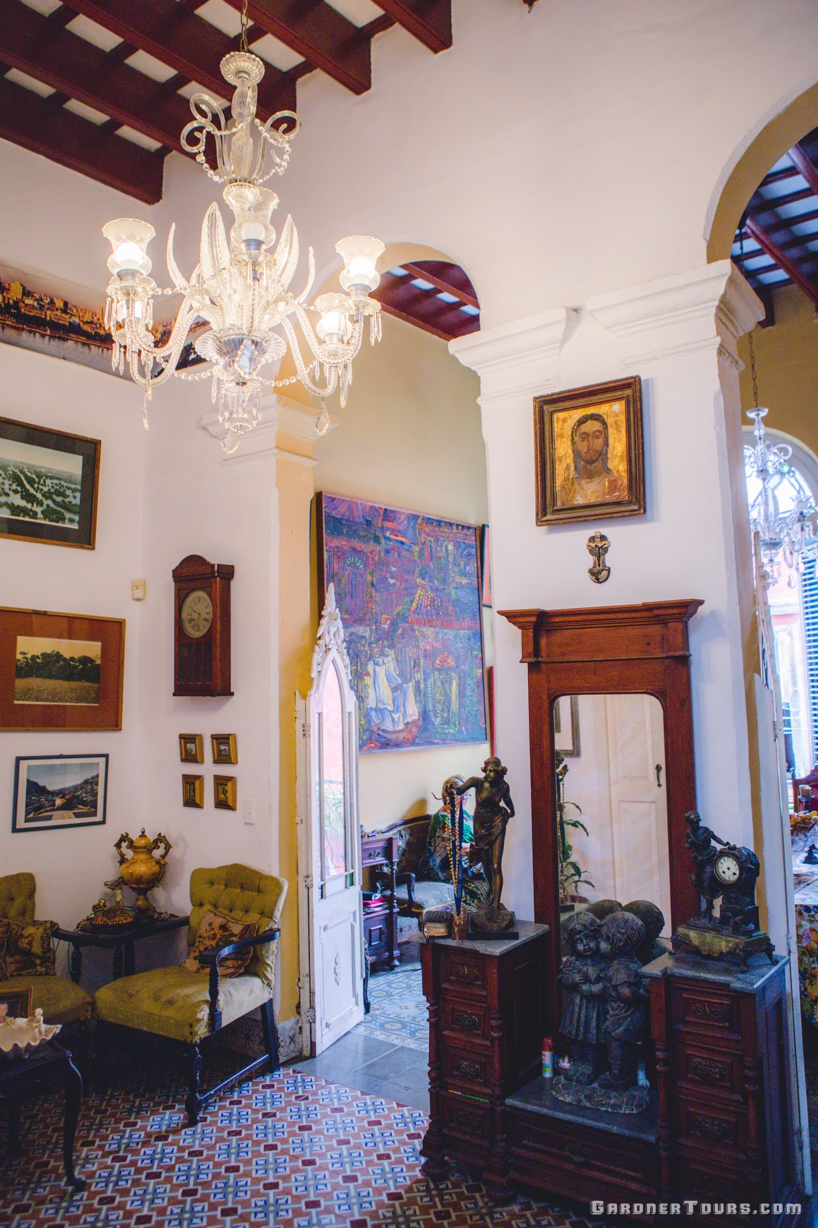 Gardner Tours Beautiful Colorful Living Room with Paintings, a Jesus Painting from the 1500s, and Ornate Tiled Floors at a Private BnB in Havana, Cuba