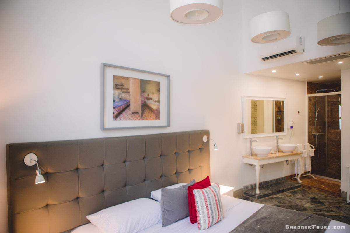 A luxurious Bedroom with a grey bed and white sheets and a Bathroom in our 4-star BnB in Havana, Cuba