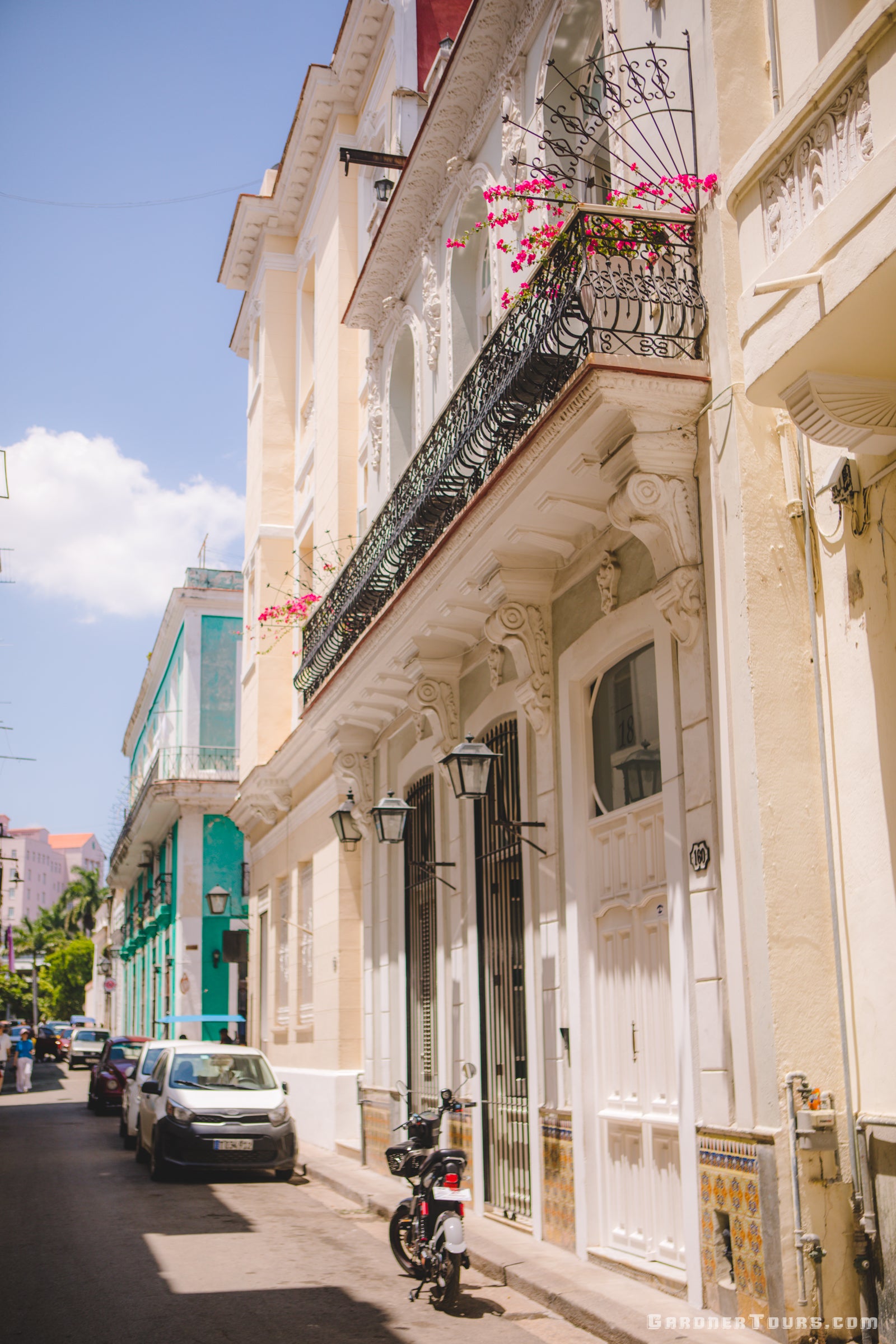 A White Luxury BnB from the Street with Black Iron Work and Flowers hanging on the balcony in Old Havana, Cuba 