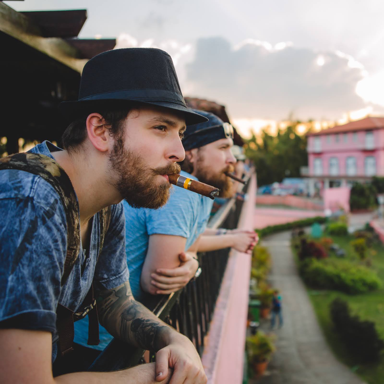 Gardner Tours Premium Cuba Cigar Tour Two friends smoking cigars and enjoying the view as they hang over the railing at the Viewpoint over Viñales Valley in Cuba