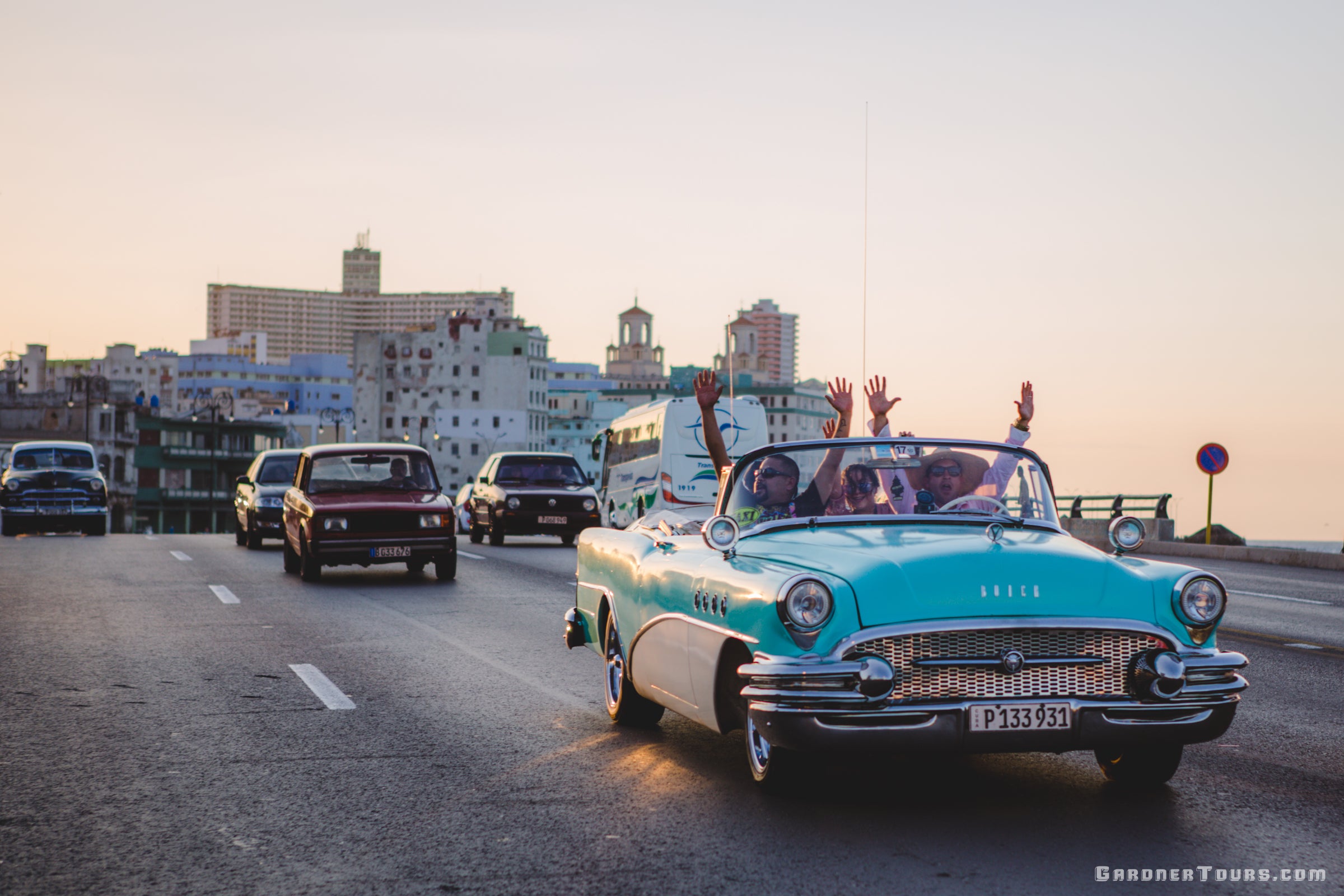 Group of Friends riding in Classic American Car Convertible with their hands in the air on the Malecon in Havana, Cuba