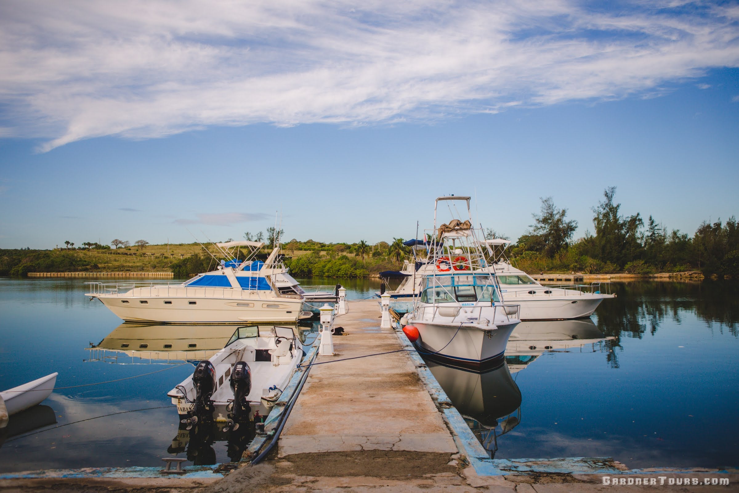 Three beautiful boats sit at dock during a calm morning waiting on their fishermen to arrive to go offshore fishing in Havana Cuba