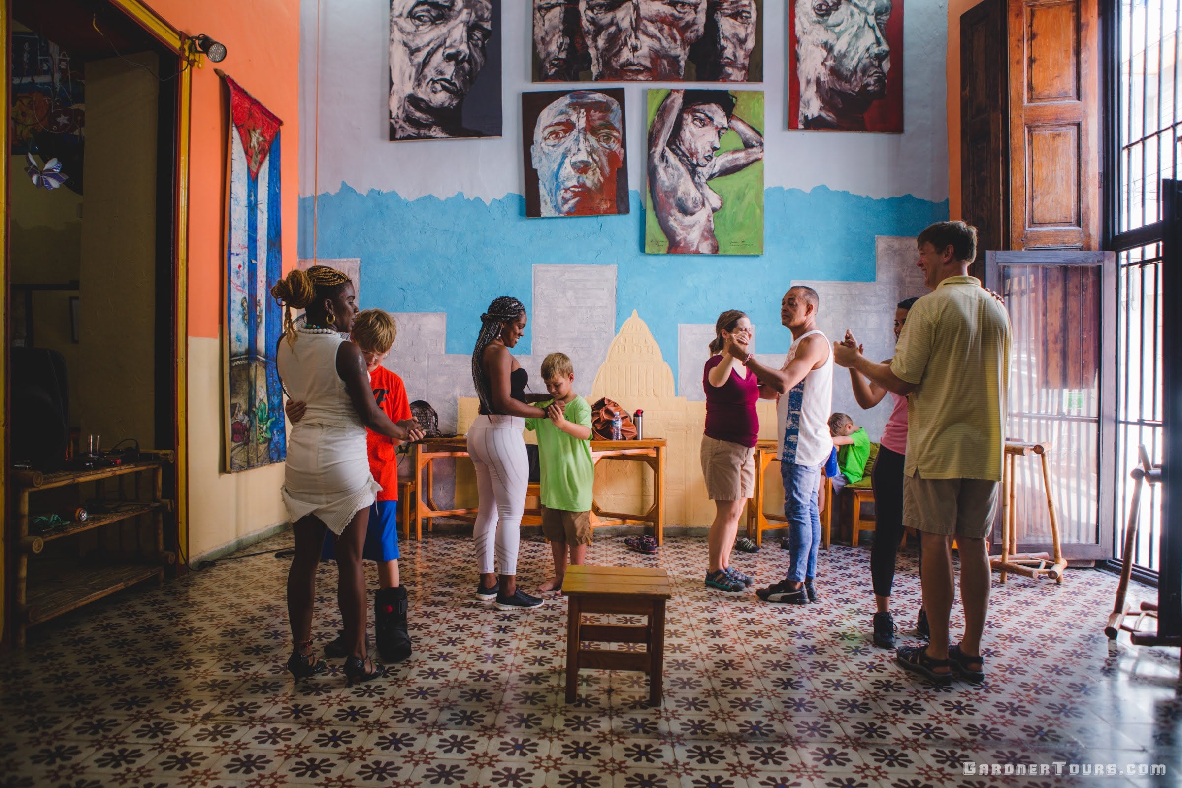Gardner Tours a beautiful sala with tiled floors and classic paintings on the wall houses a family learning to dance salsa in Old Havana Cuba
