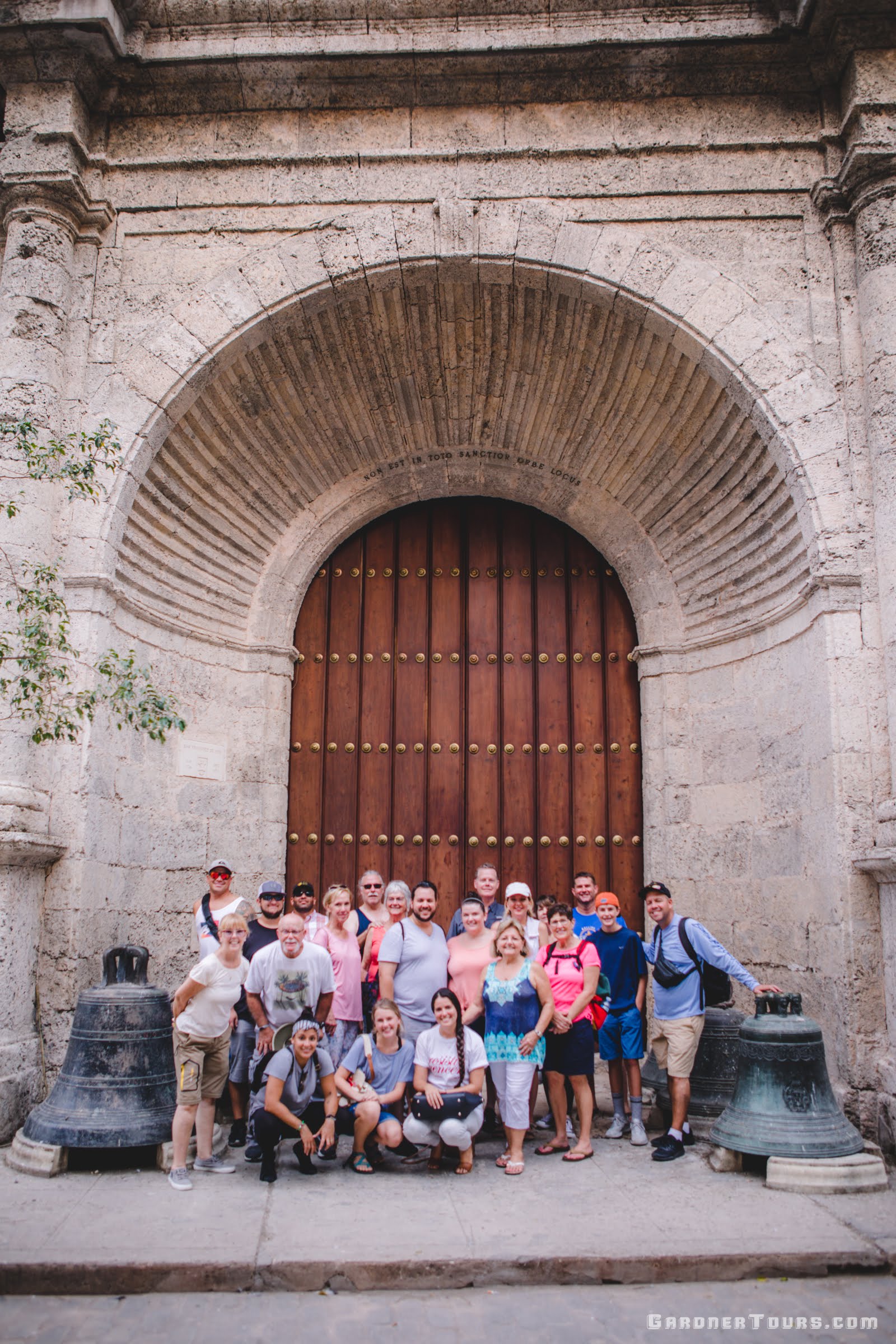 Gardner Tours Cuban Tour Guide Yunior with a large group of travelers from the USA in Old Havana Cuba by the big side door of the Convent of San Francisco de Asis