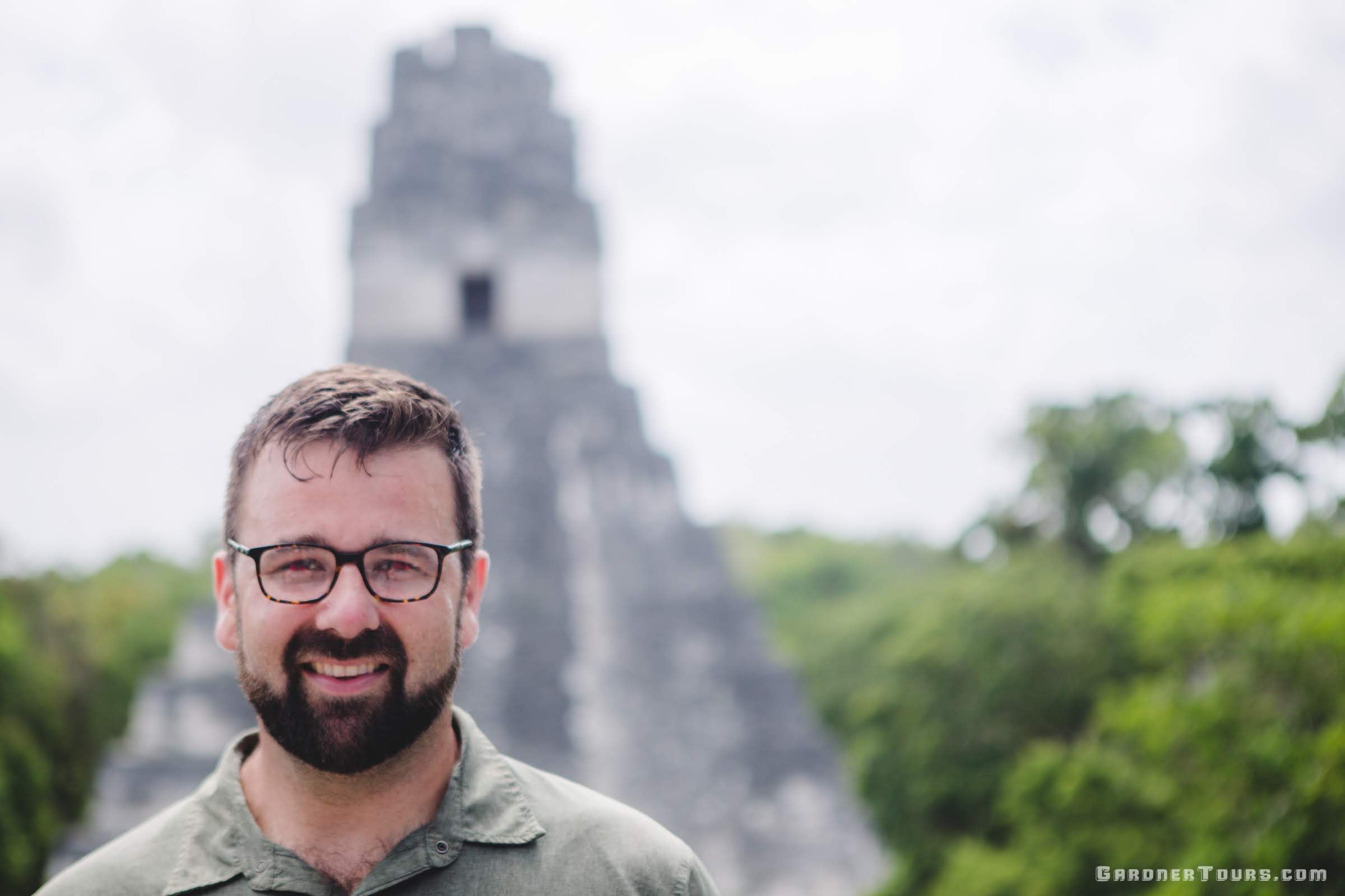 Gardner Tours Owner and Tour Guide Colby Gardner smiling in front of a Mayan pyramid in Tikal National Park in Tikal, Guatemala