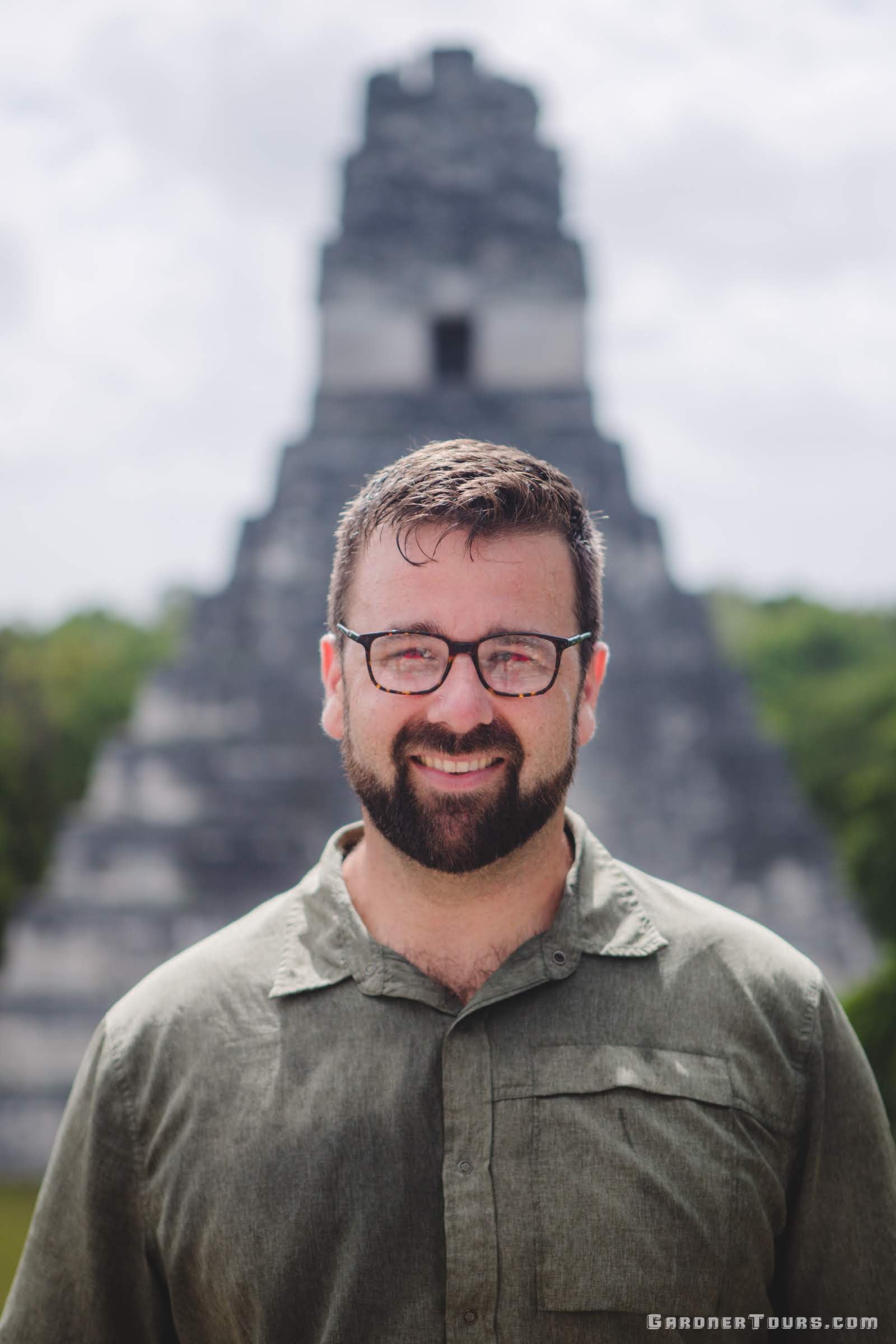 Gardner Tours Owner and Tour Guide Colby Gardner smiling big in front of one of the pyramids in Tikal National Park in Tikal, Guatemala