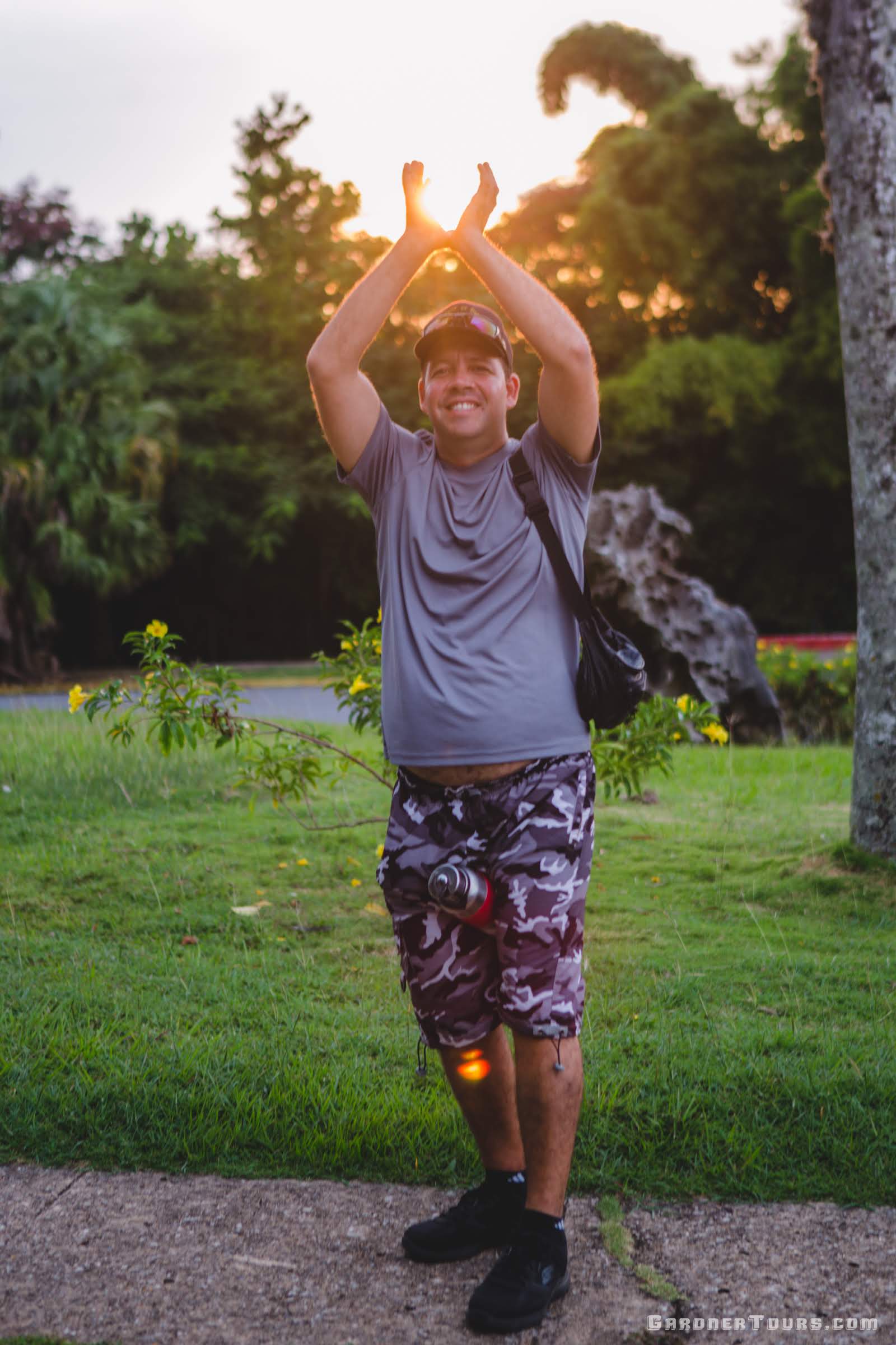 Gardner Tours Cuban Tour Guide Yunior smiling as he holds the setting sun in his hands over his head in Viñales, Cuba