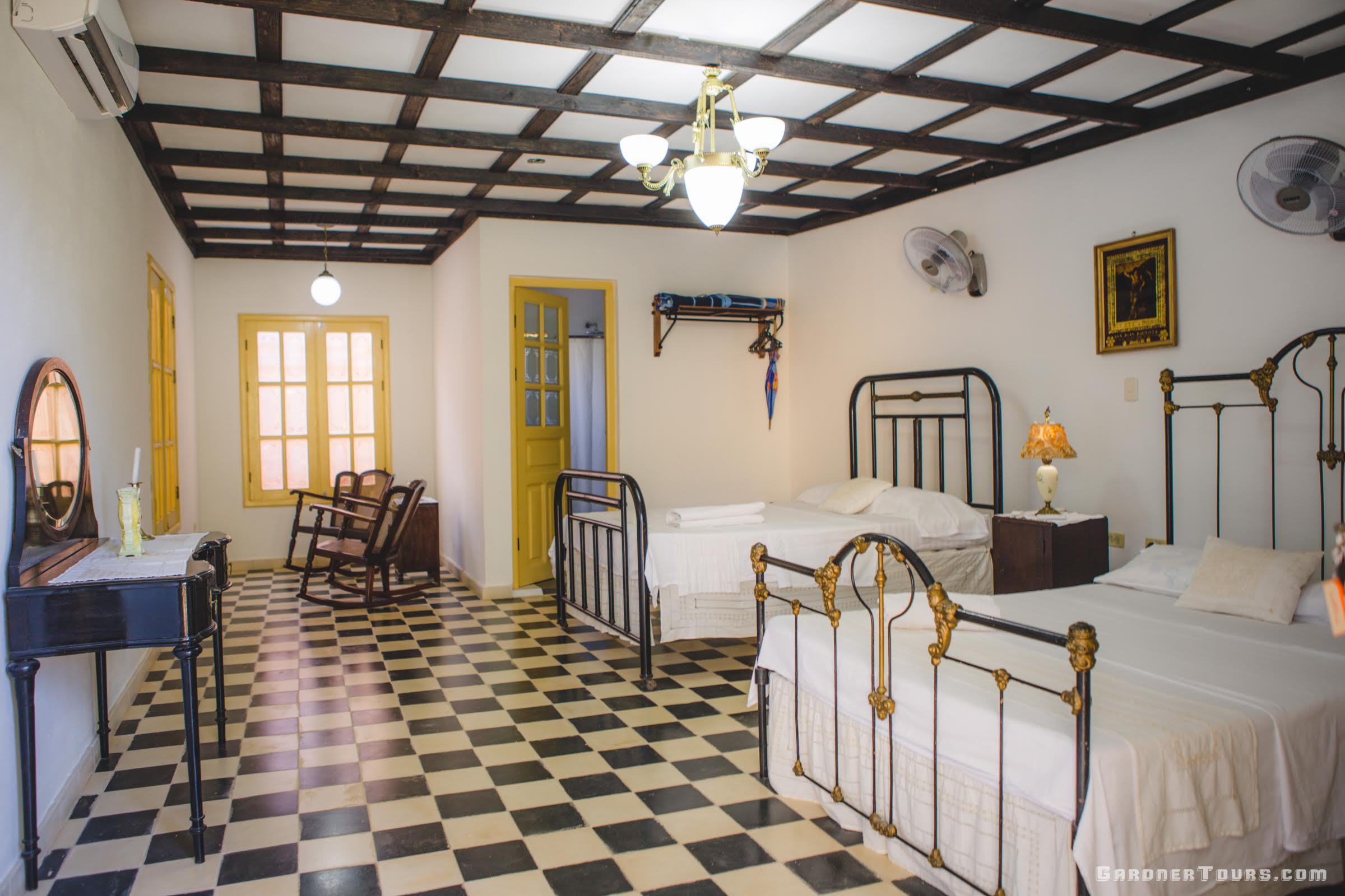 Cuba Luxury Tours Spacious black, white, and gold antique bedroom with two big beds at Toña in Trinidad, Cuba