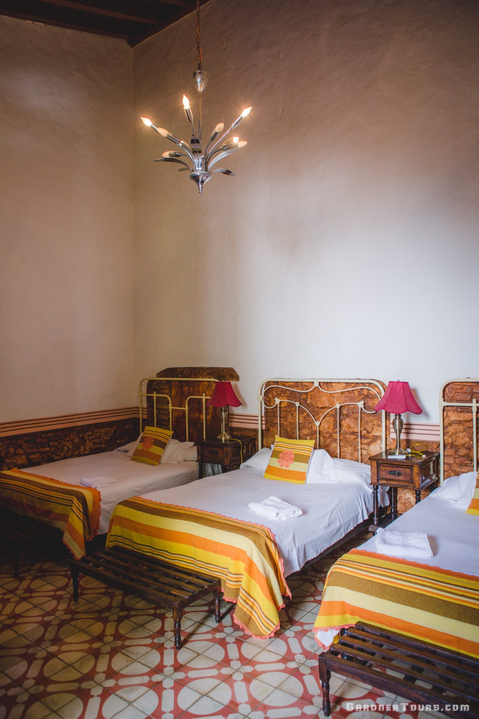Large brown and white antique bedroom with three big beds at a Casa Particular BnB in Trinidad, Cuba