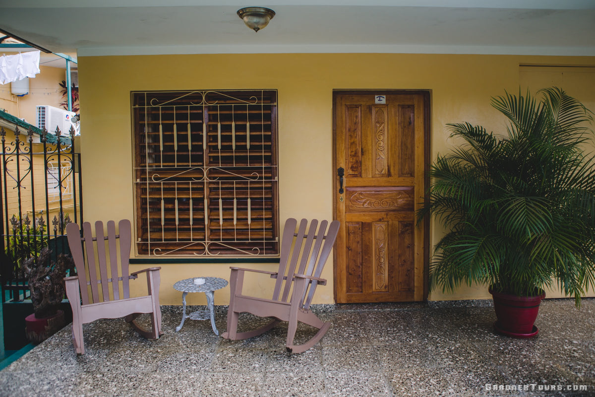 Beautiful yellow and green front porch with brown rocking chairs at a 3-star BnB in Vinales Cuba